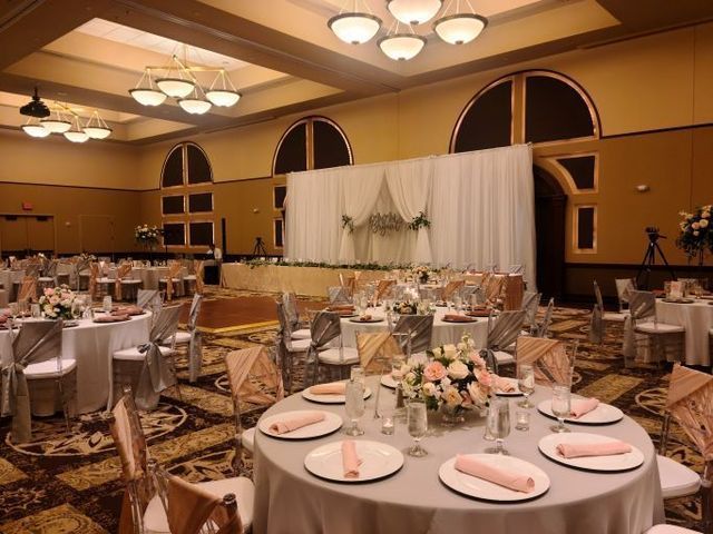A banquet hall set for a wedding reception with round tables, white tablecloths, floral centerpieces, and white draping.