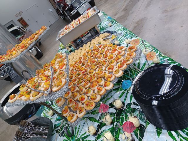 A buffet table with appetizers topped with colorful salsa, served on a tropical print tablecloth near a stack of plates.