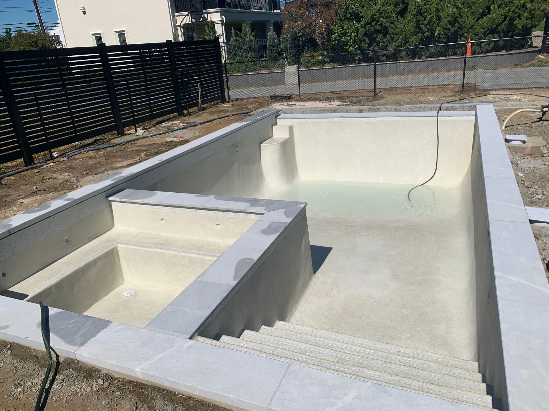 A large swimming pool with stairs and a fence in the background.