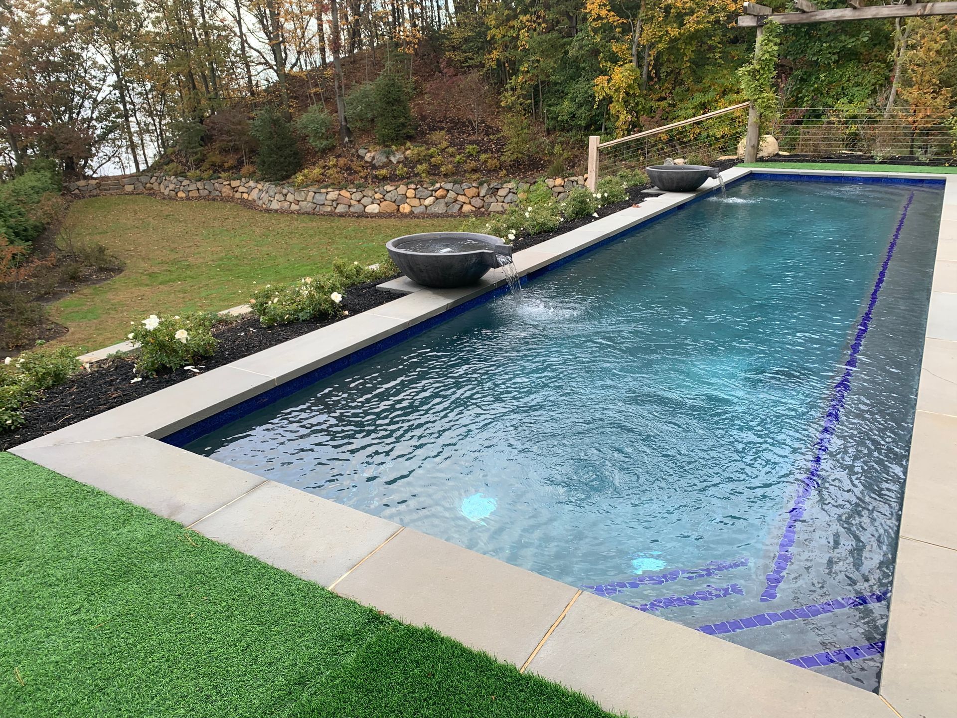 A large swimming pool surrounded by grass and trees in a backyard.