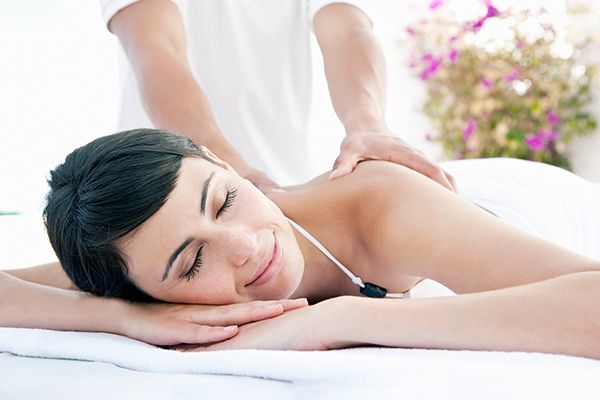 A woman is laying on a bed getting a massage from a massage therapist.