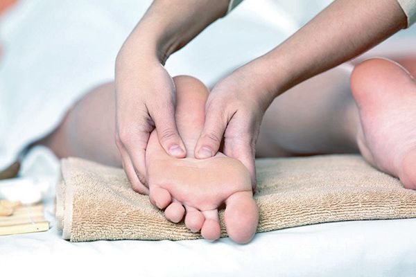 A person is getting a foot massage on a bed.
