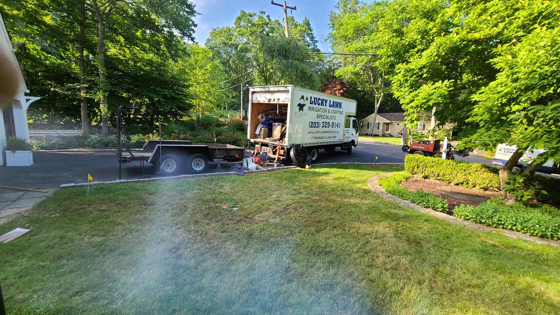 A white moving truck is parked in the grass in front of a house.