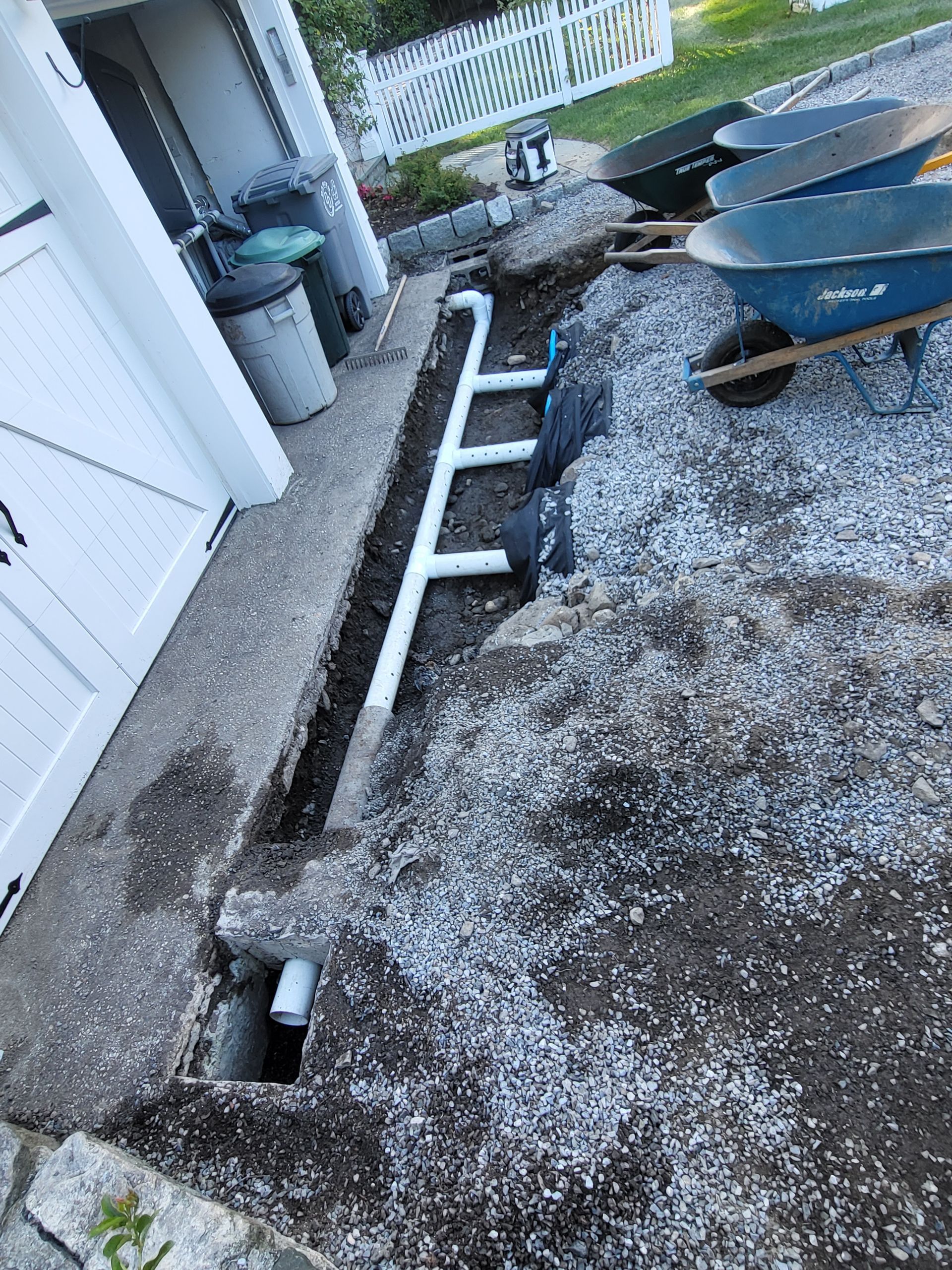 A wheelbarrow is sitting in the dirt next to a pipe.