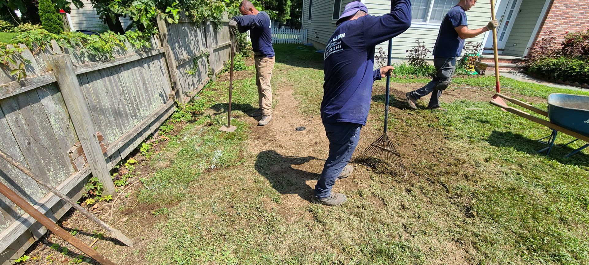 A group of people are working in a yard next to a fence.