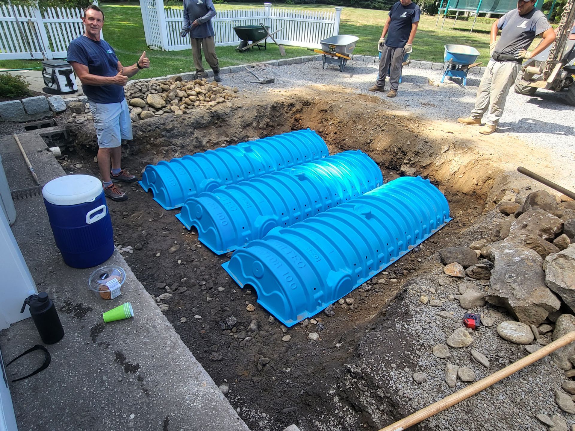 A group of men are working on a septic system in a yard.
