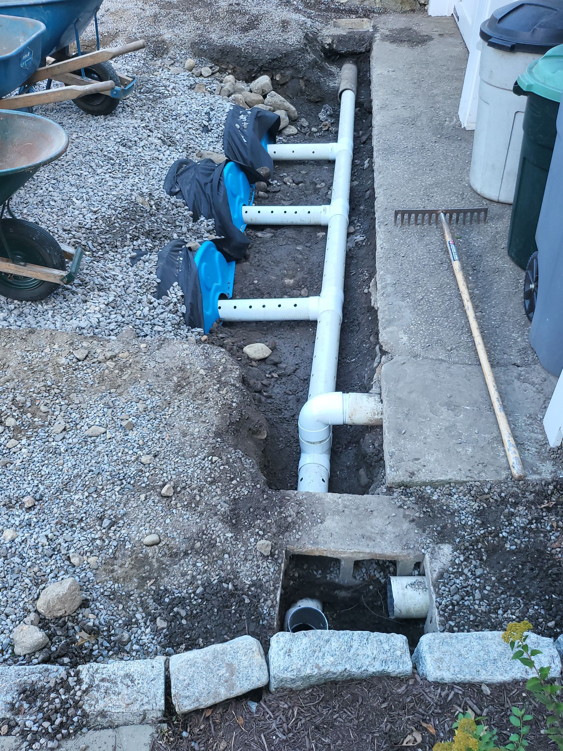 A drain pipe is being installed in a hole in the ground.