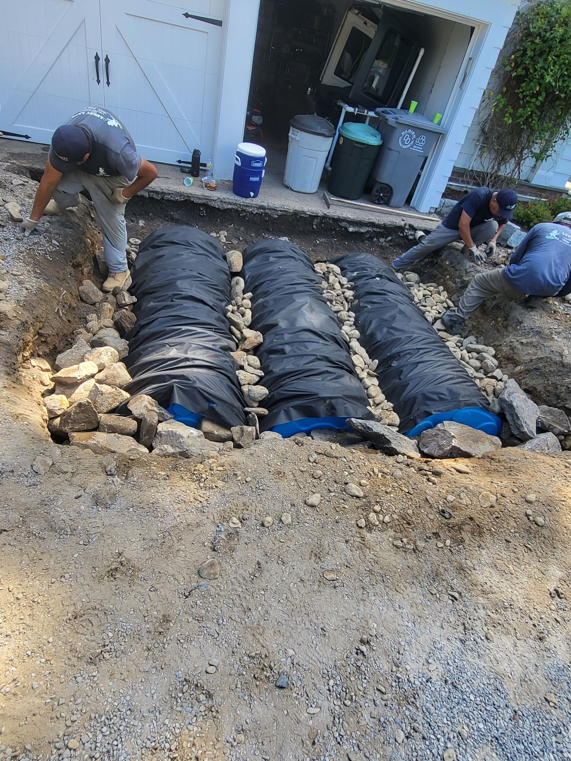 A group of men are working on a septic system in the dirt.