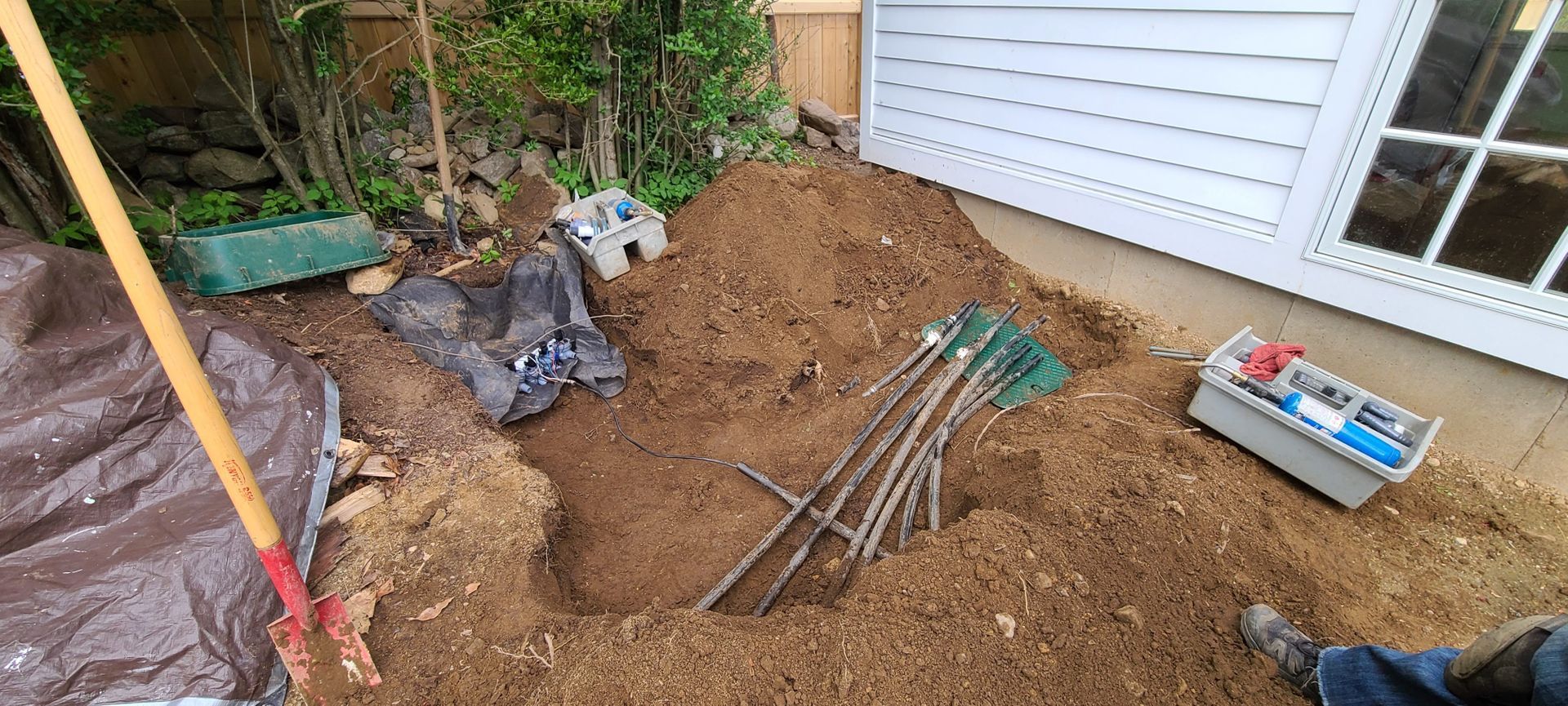 A person is digging a hole in the dirt in front of a house.