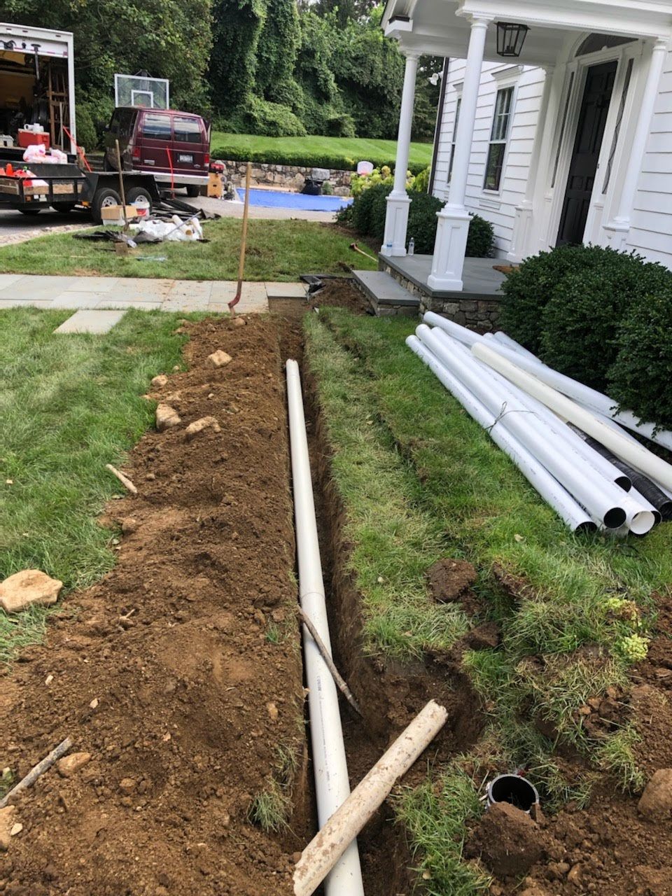 A pipe is being installed in the dirt in front of a house.