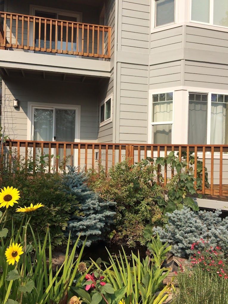 A house with a deck and flowers in front of it