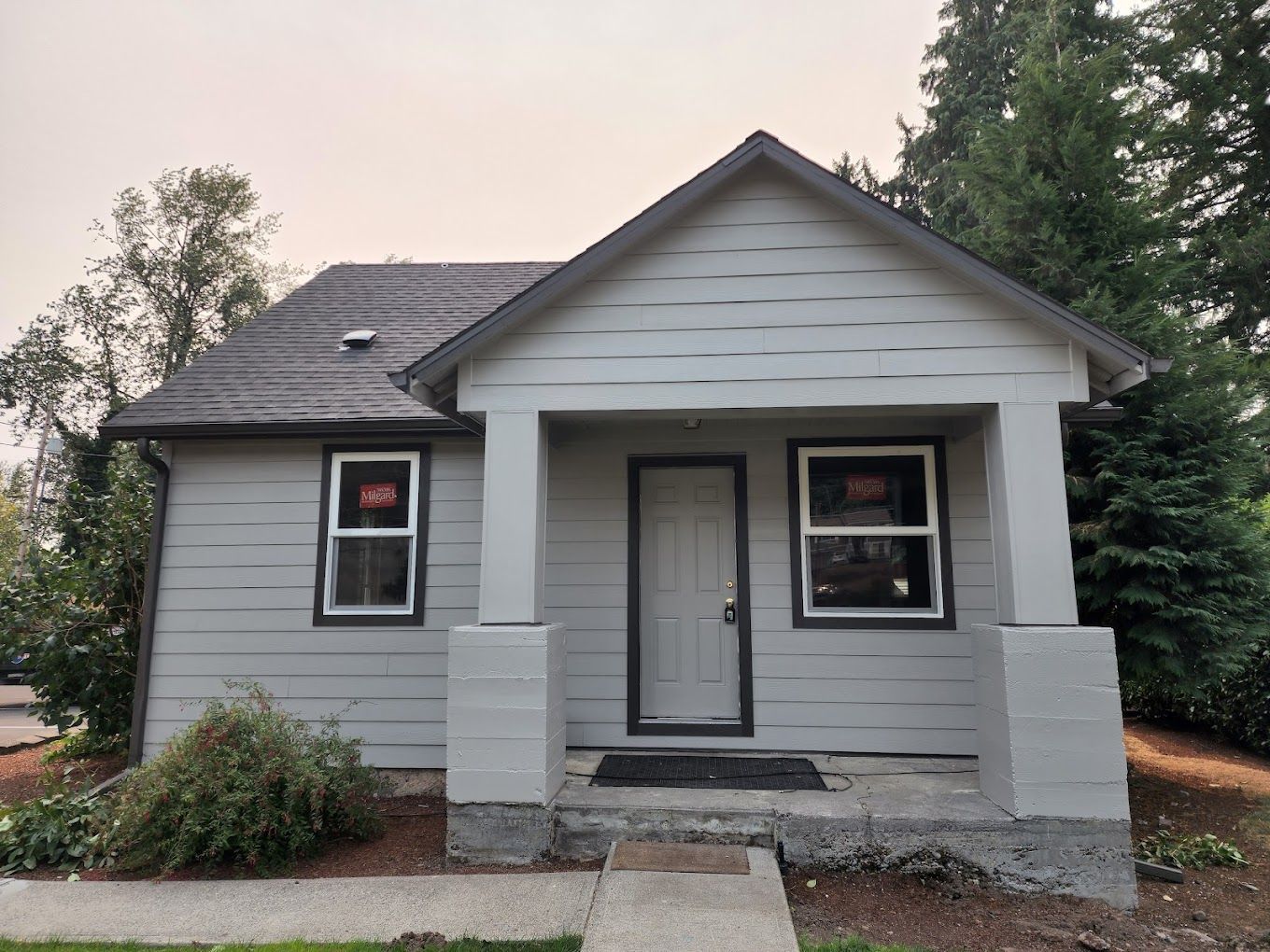 A small white house with a porch and two windows