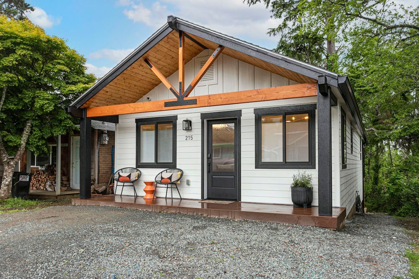A small white house with a porch and chairs in front of it.