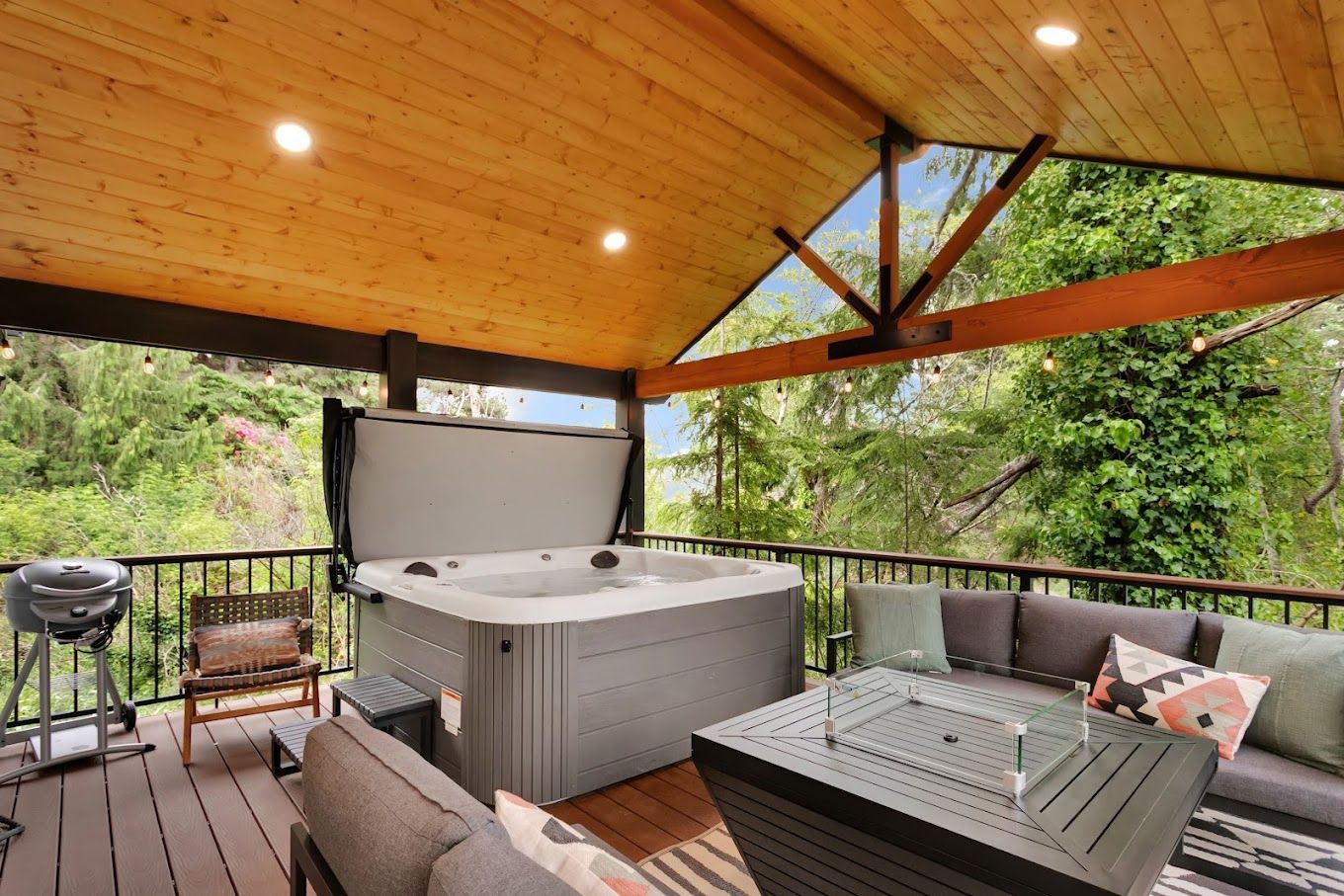 There is a hot tub on the deck with the lid open.