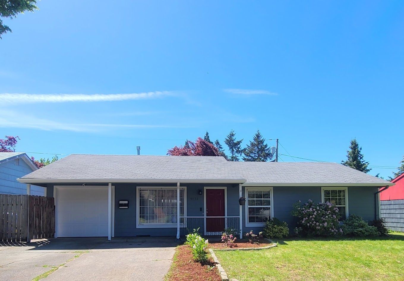 A blue house with a red door and a white garage door.