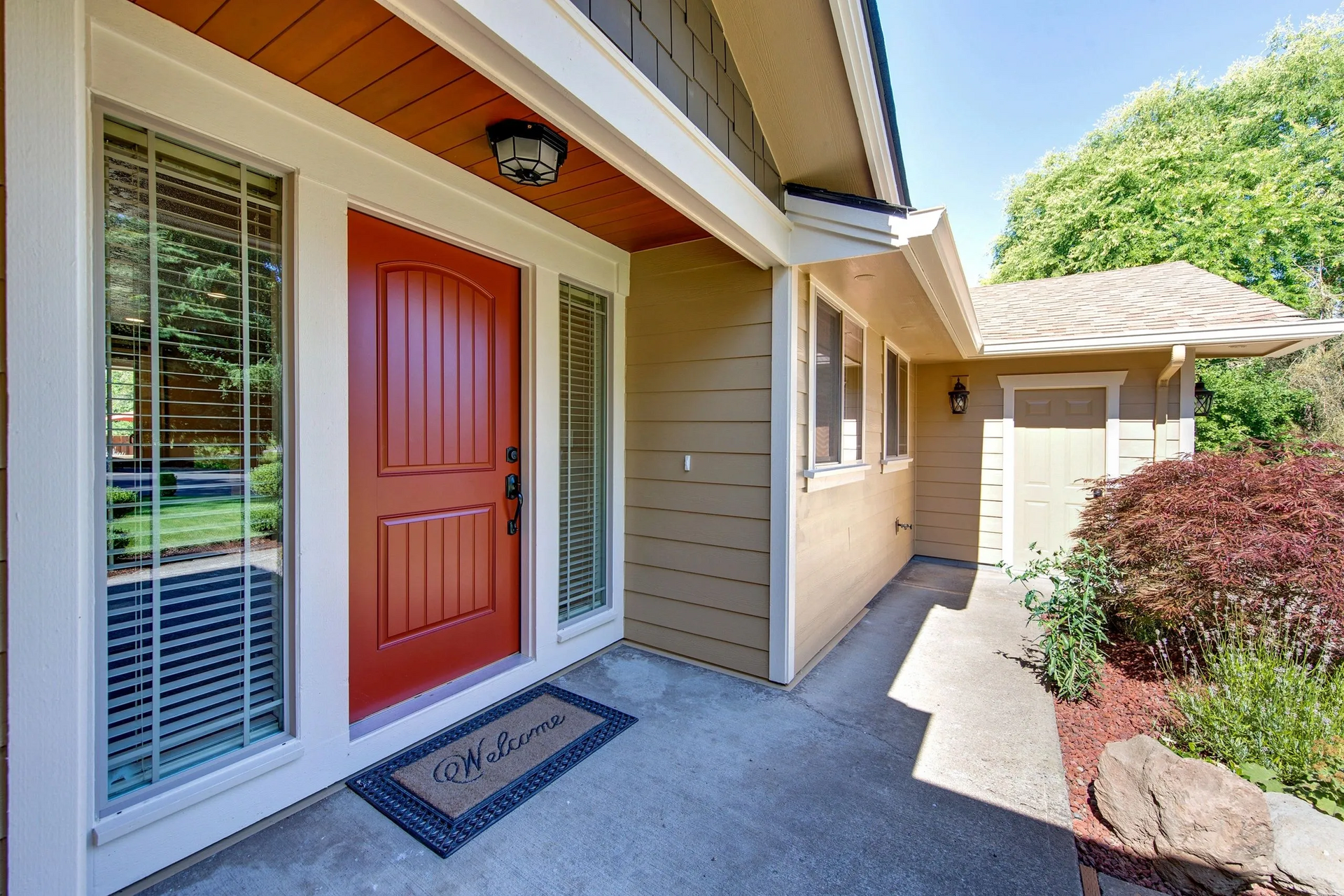 The front door of a house with a red door and a welcome mat.