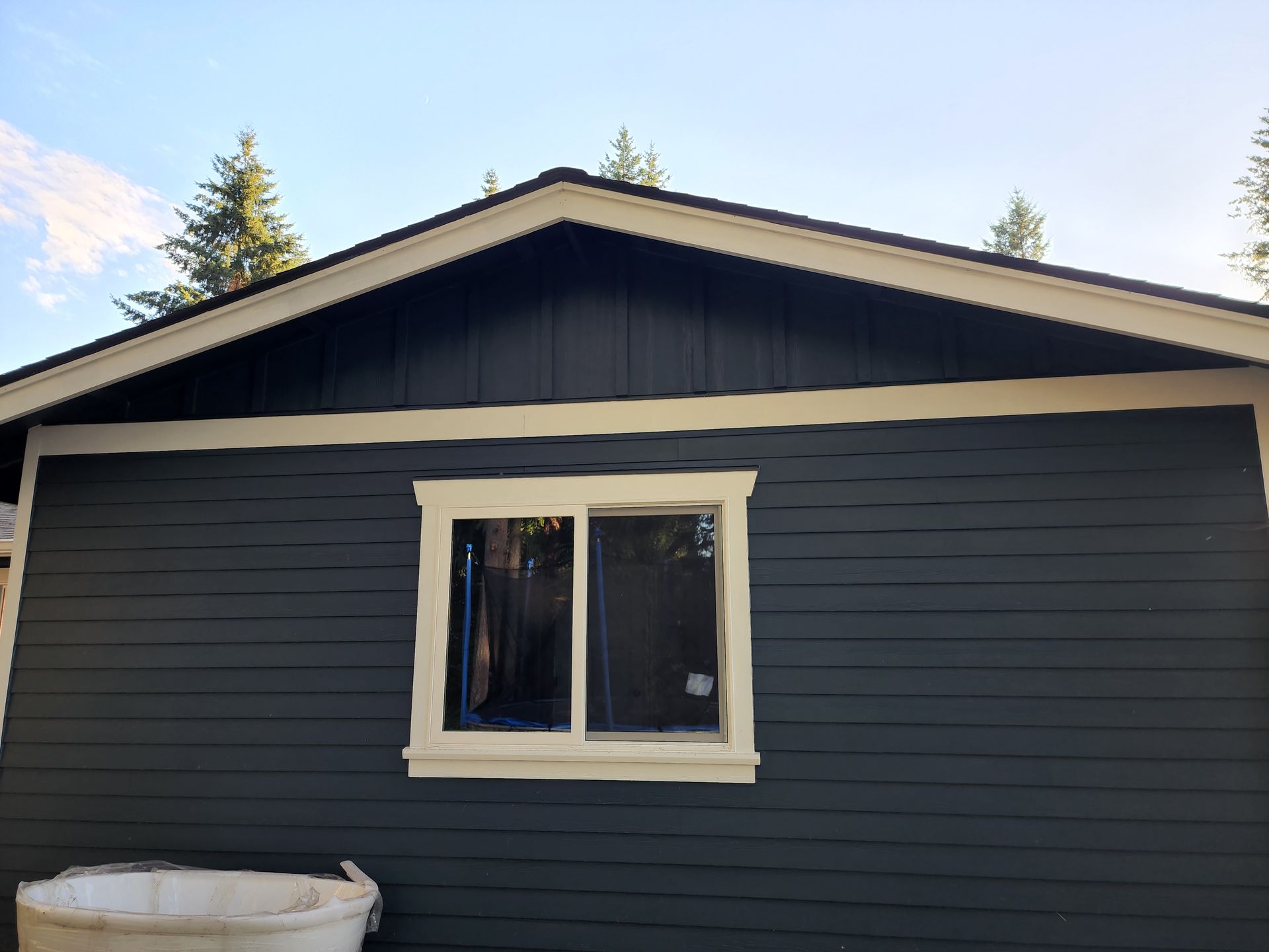 A black house with a white trim and a window.