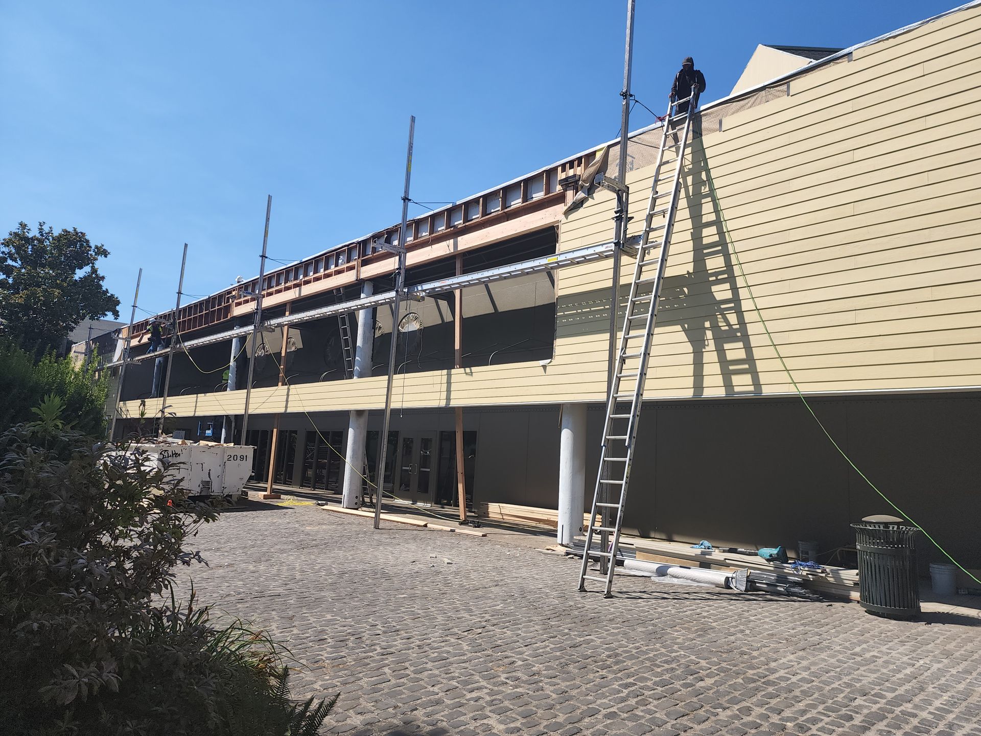 A man on a ladder is working on the roof of a building