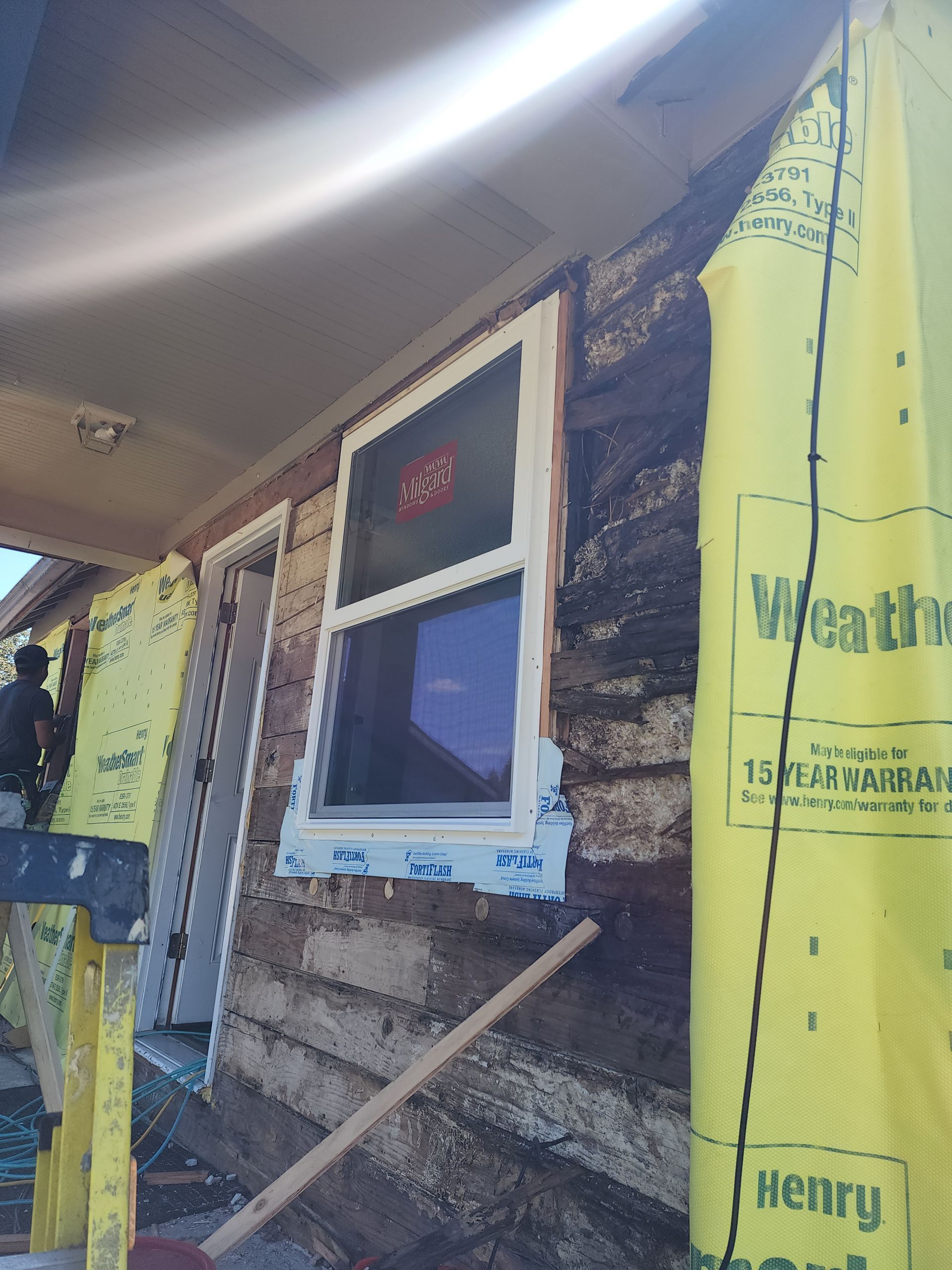A window is being installed on the side of a log cabin.