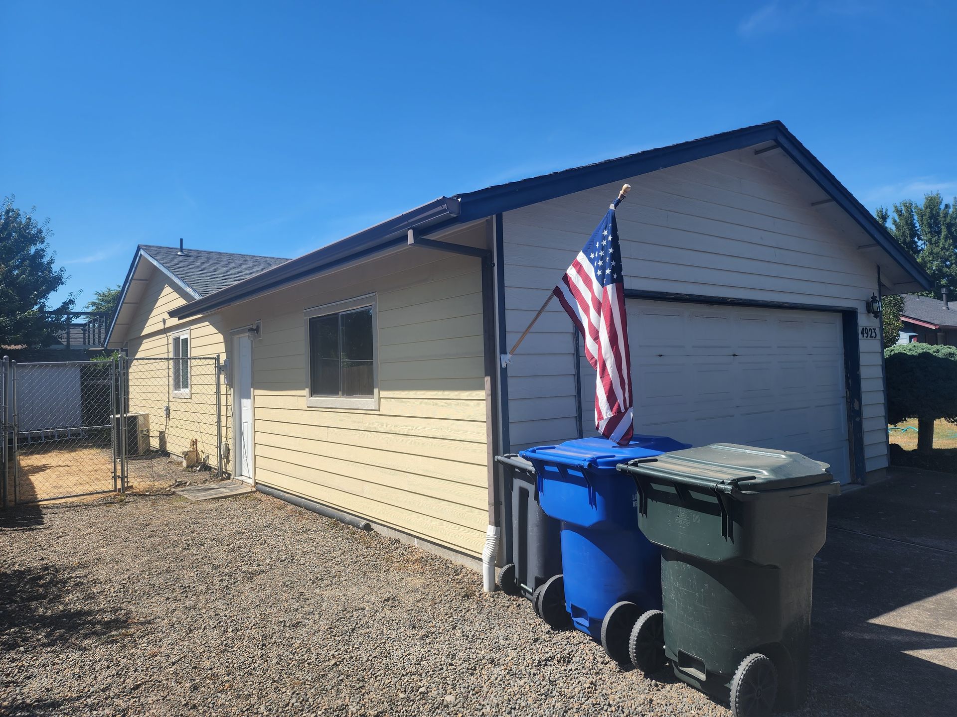 A house with a garage and trash cans in front of it