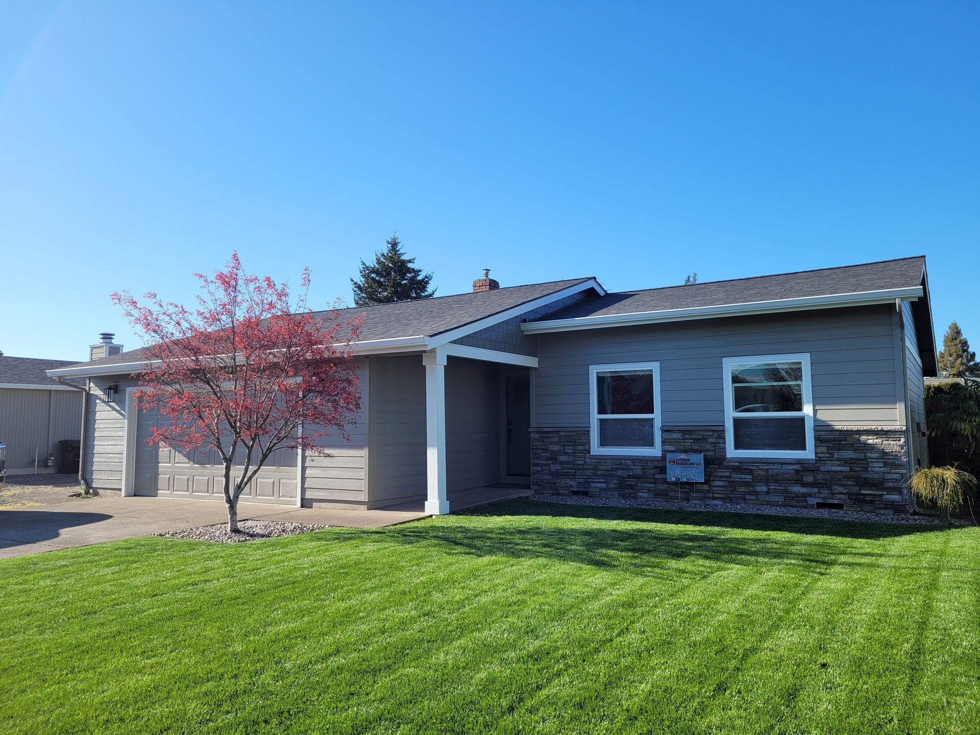 A house with a tree in front of it and a lush green lawn.