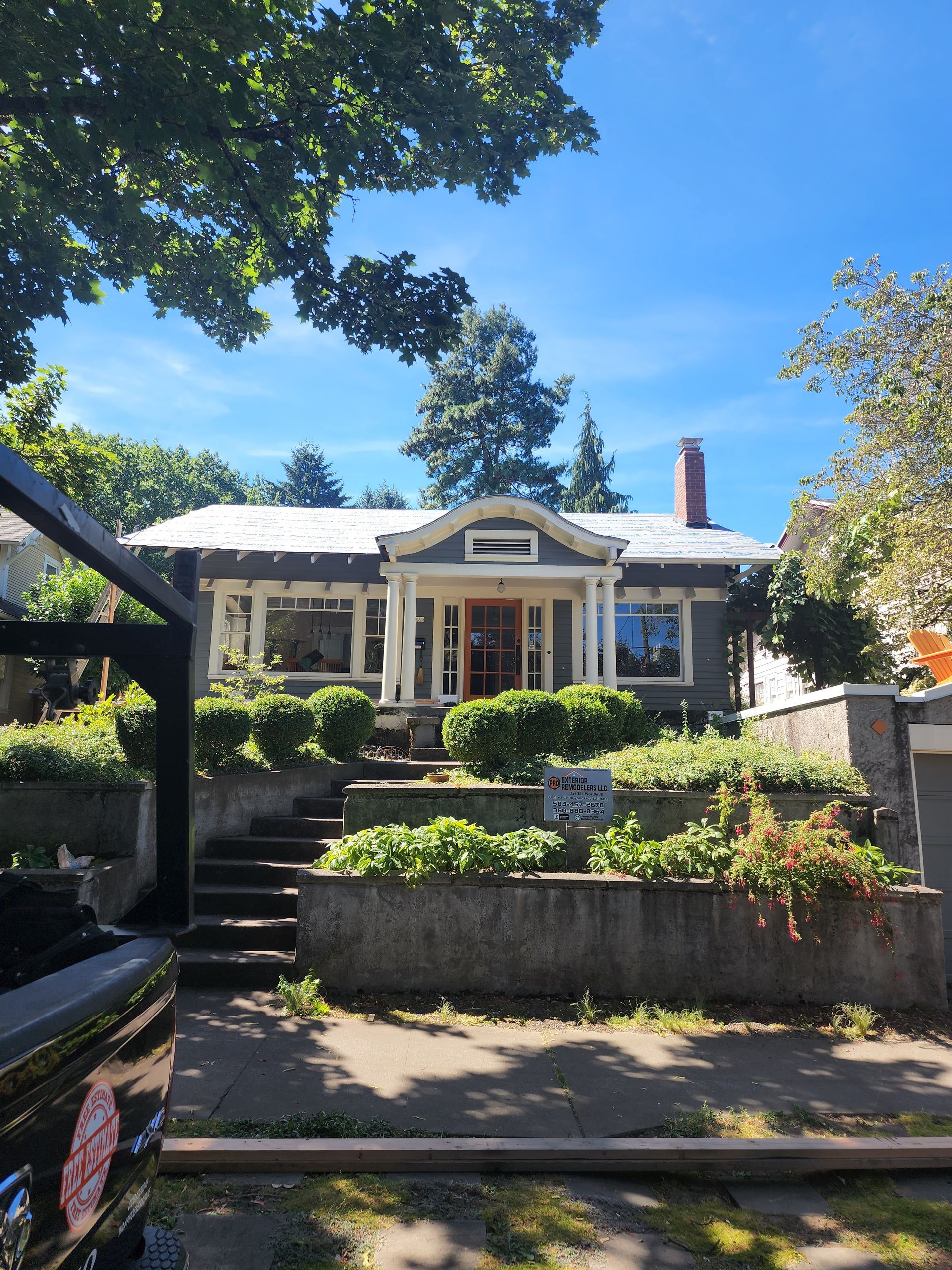A house with a white roof is surrounded by trees and bushes