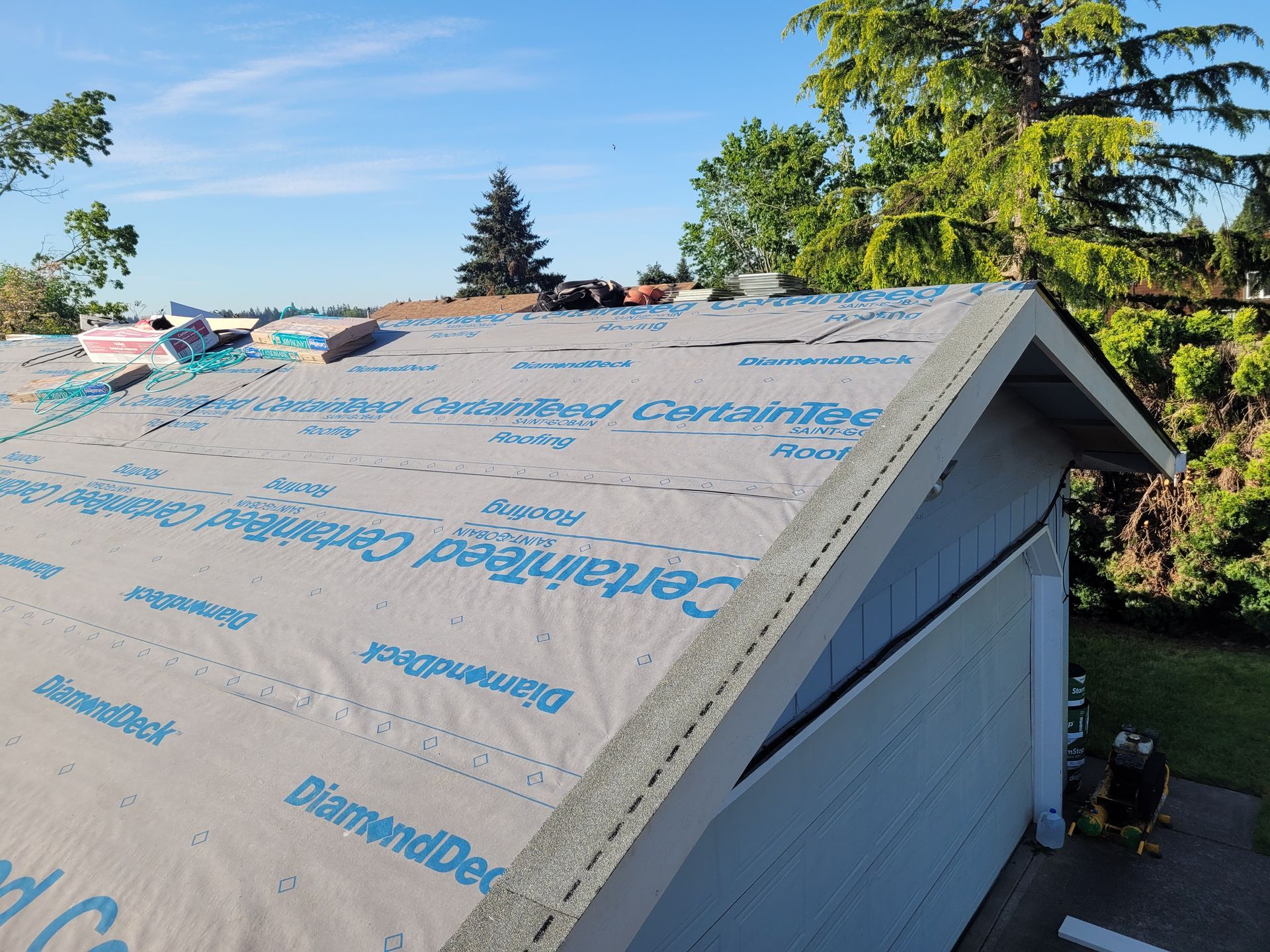 The roof of a garage is being covered with a roofing material.