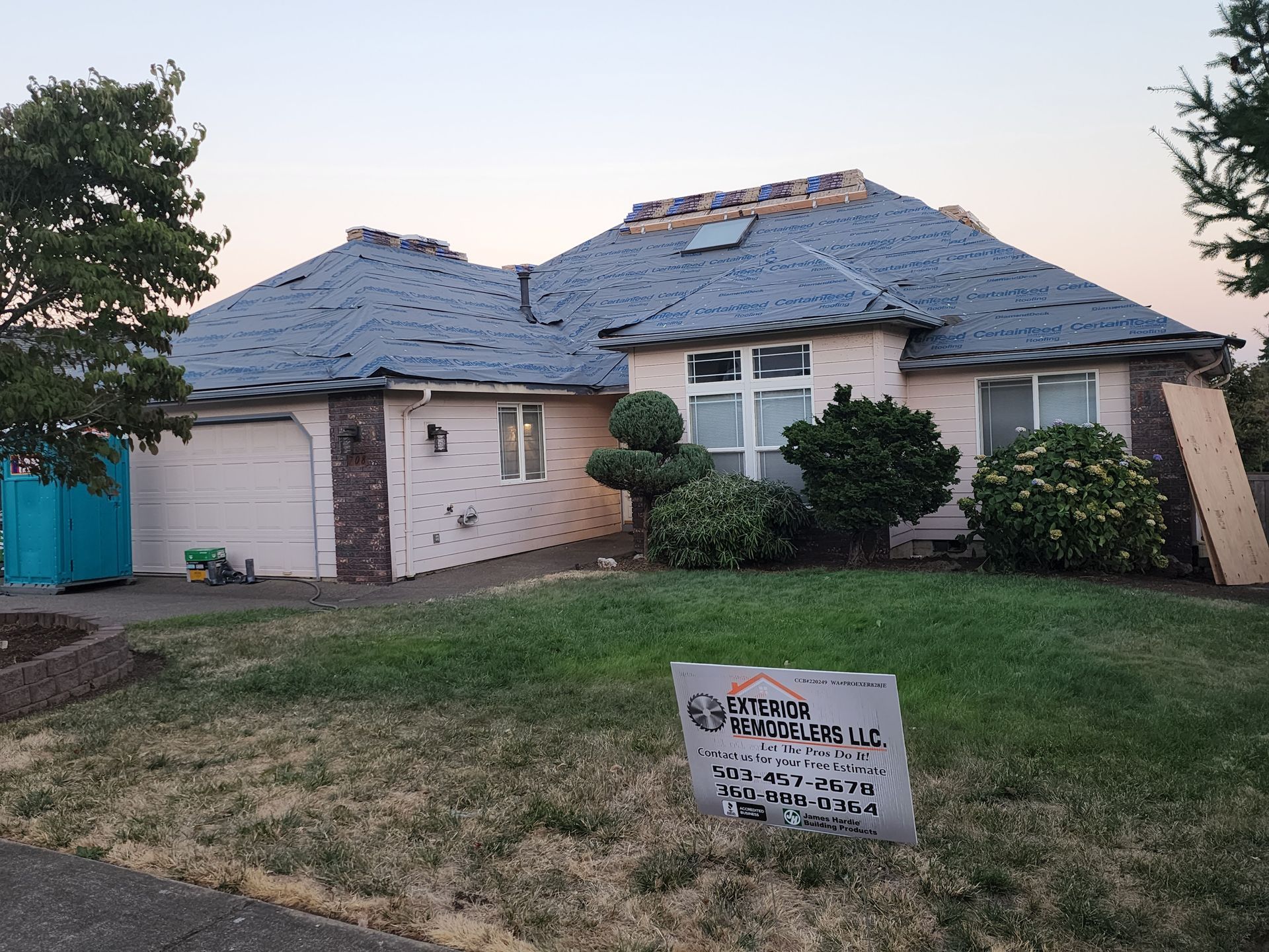 A white house with a blue roof and a sign in front of it.