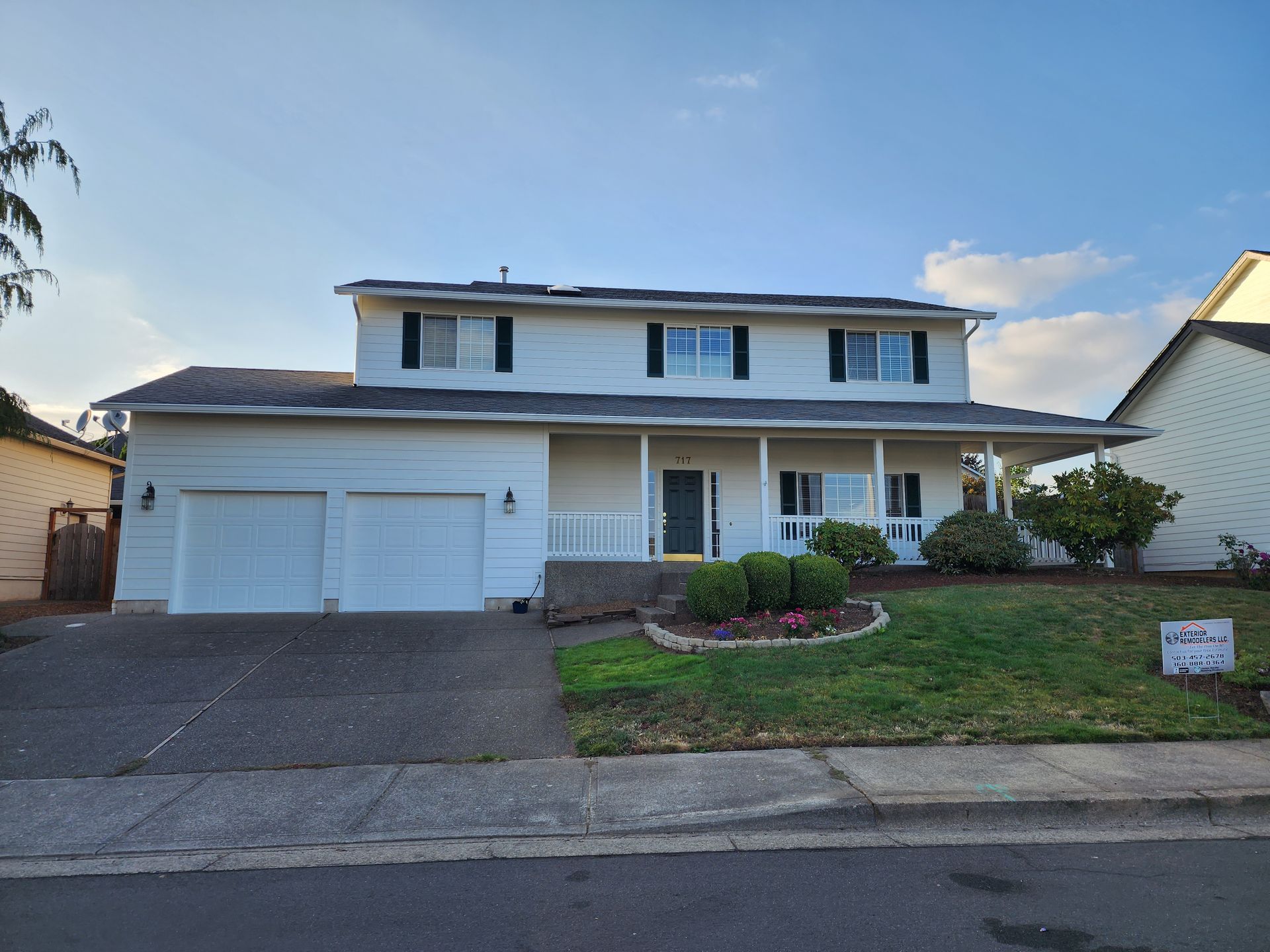 A large white house with two garage doors and a porch.