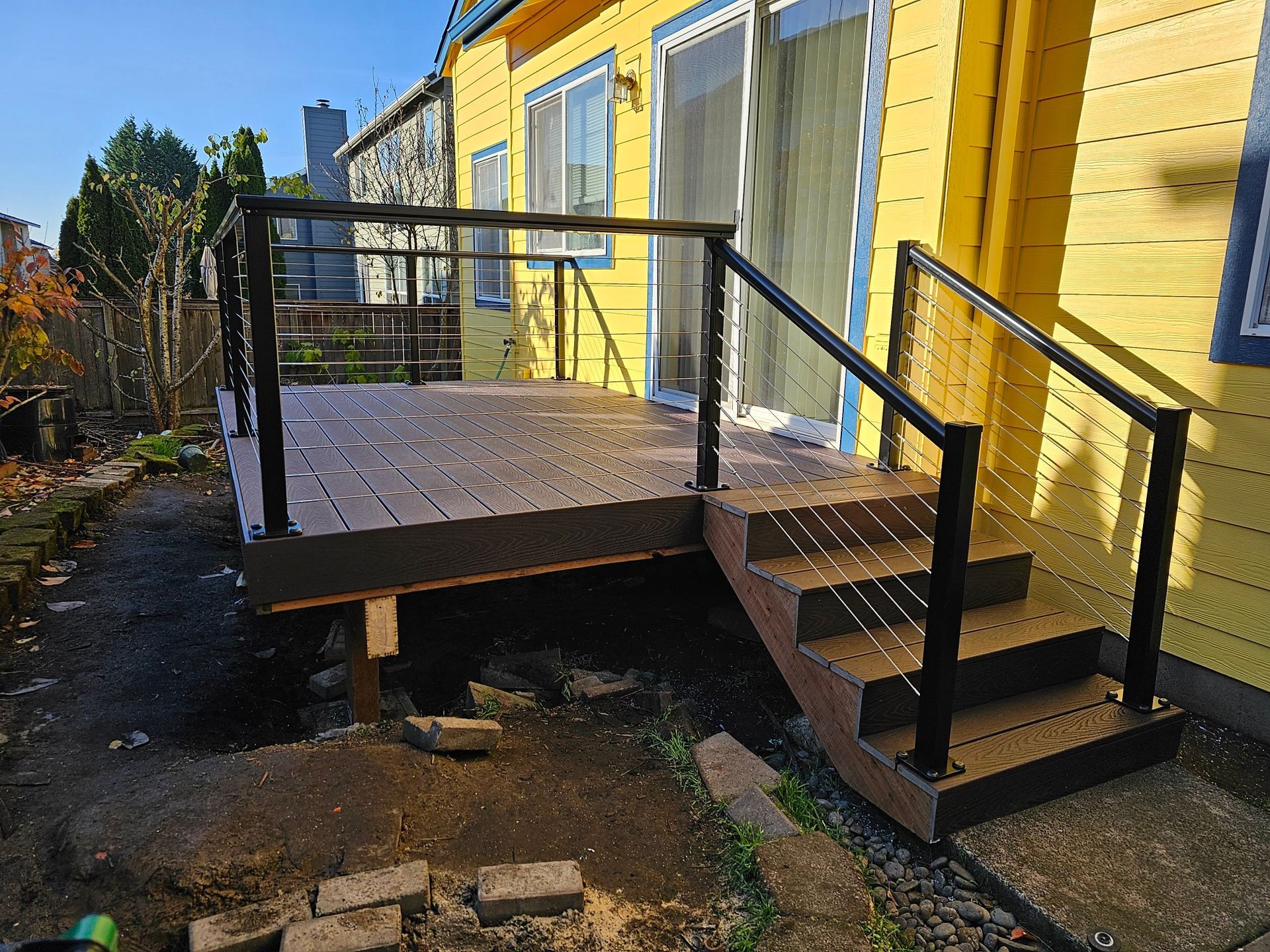 A yellow house with a deck and stairs in front of it