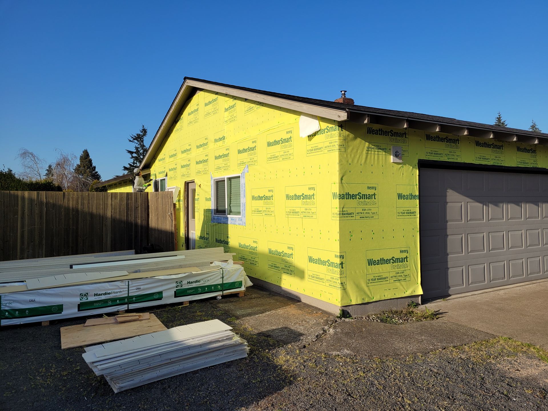 A house is being built with yellow insulation and a garage door.