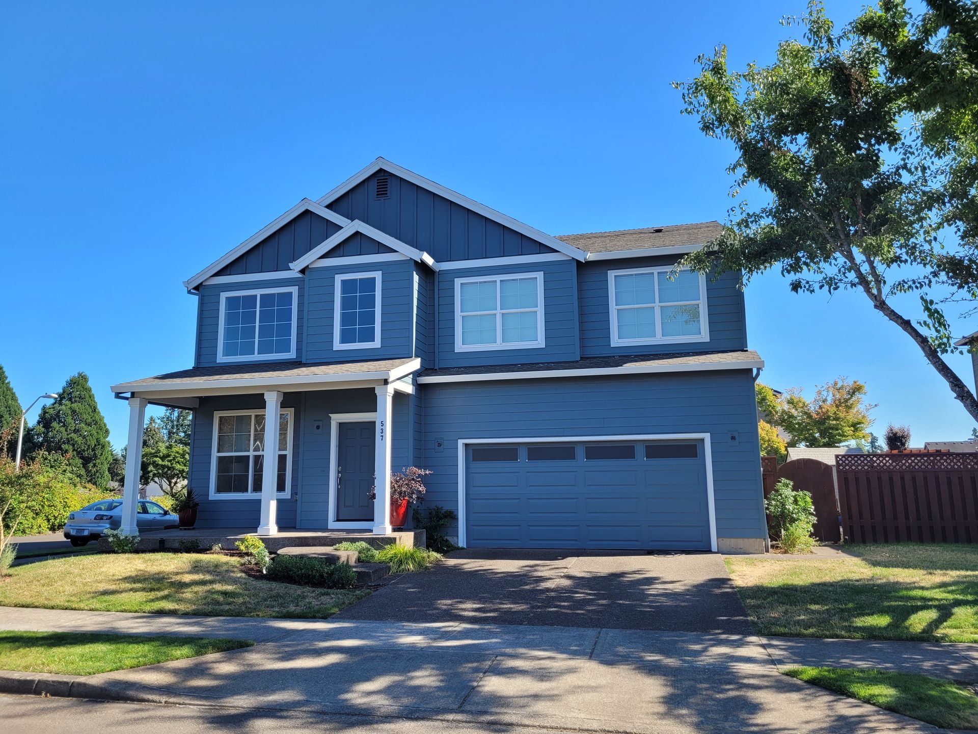 A large blue house with a garage and a blue sky in the background.