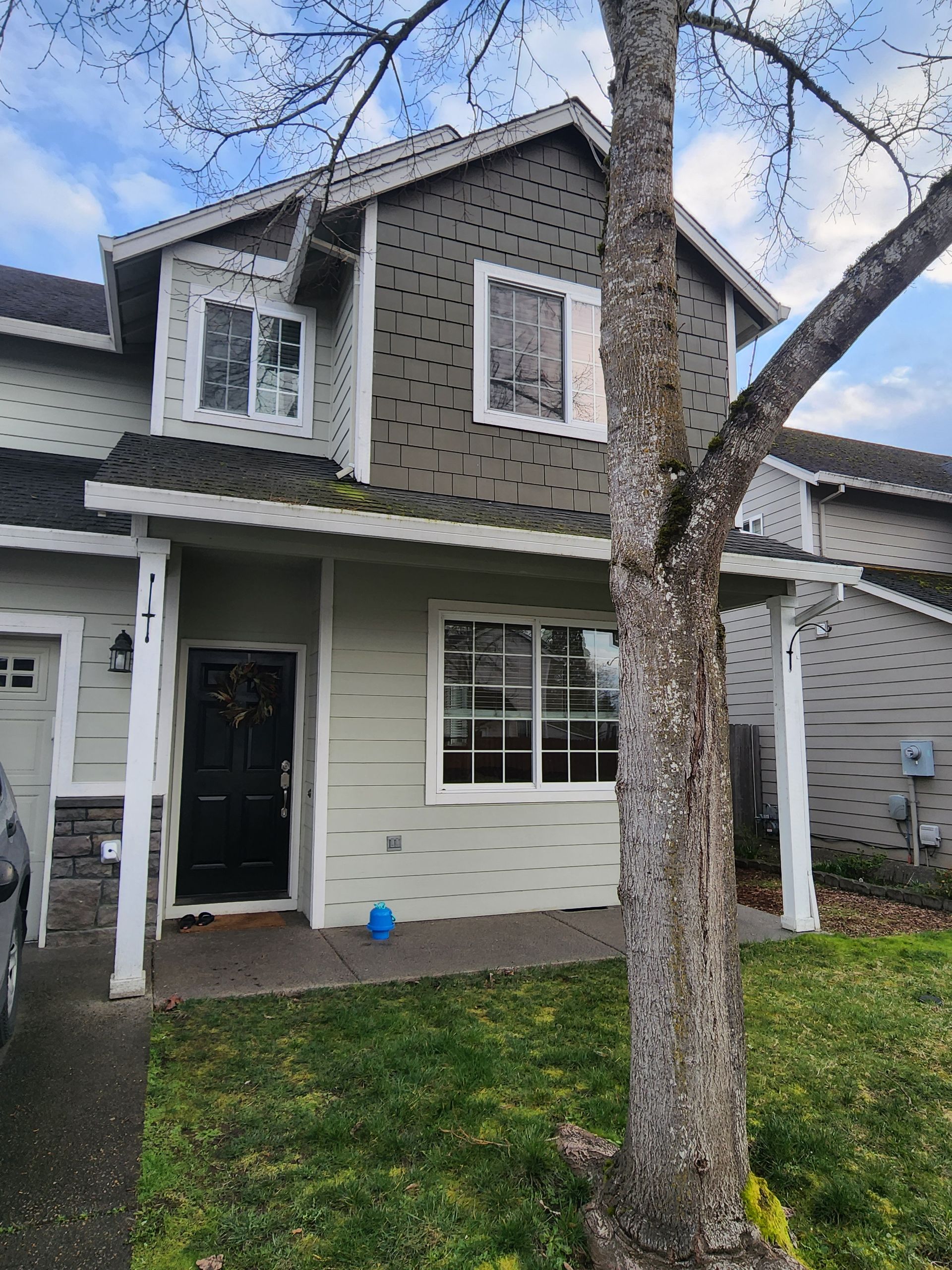 A house with a tree in front of it and a car parked in front of it.