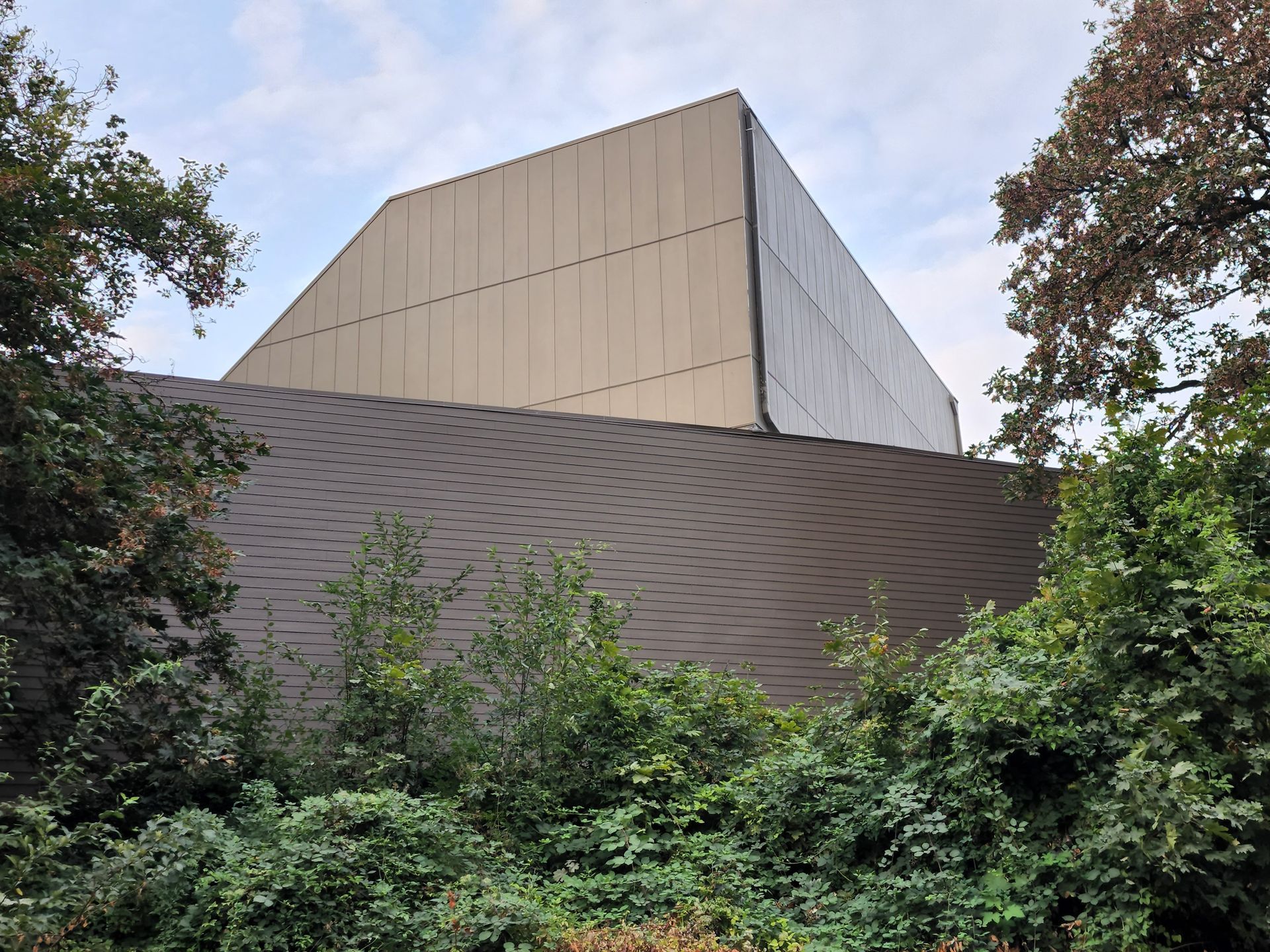A large building with a pyramid shaped roof is surrounded by trees