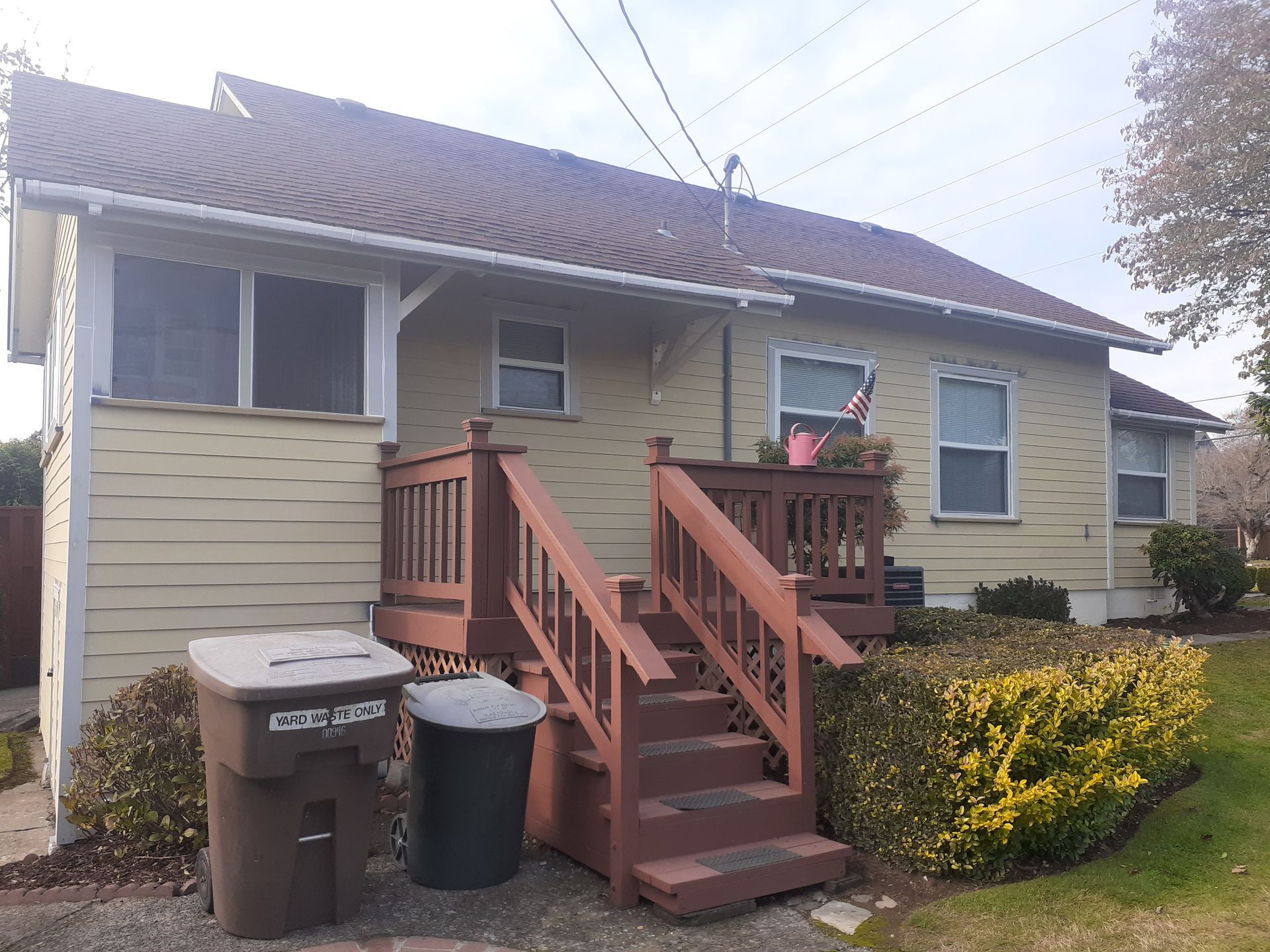 The back of a house with stairs and a trash can