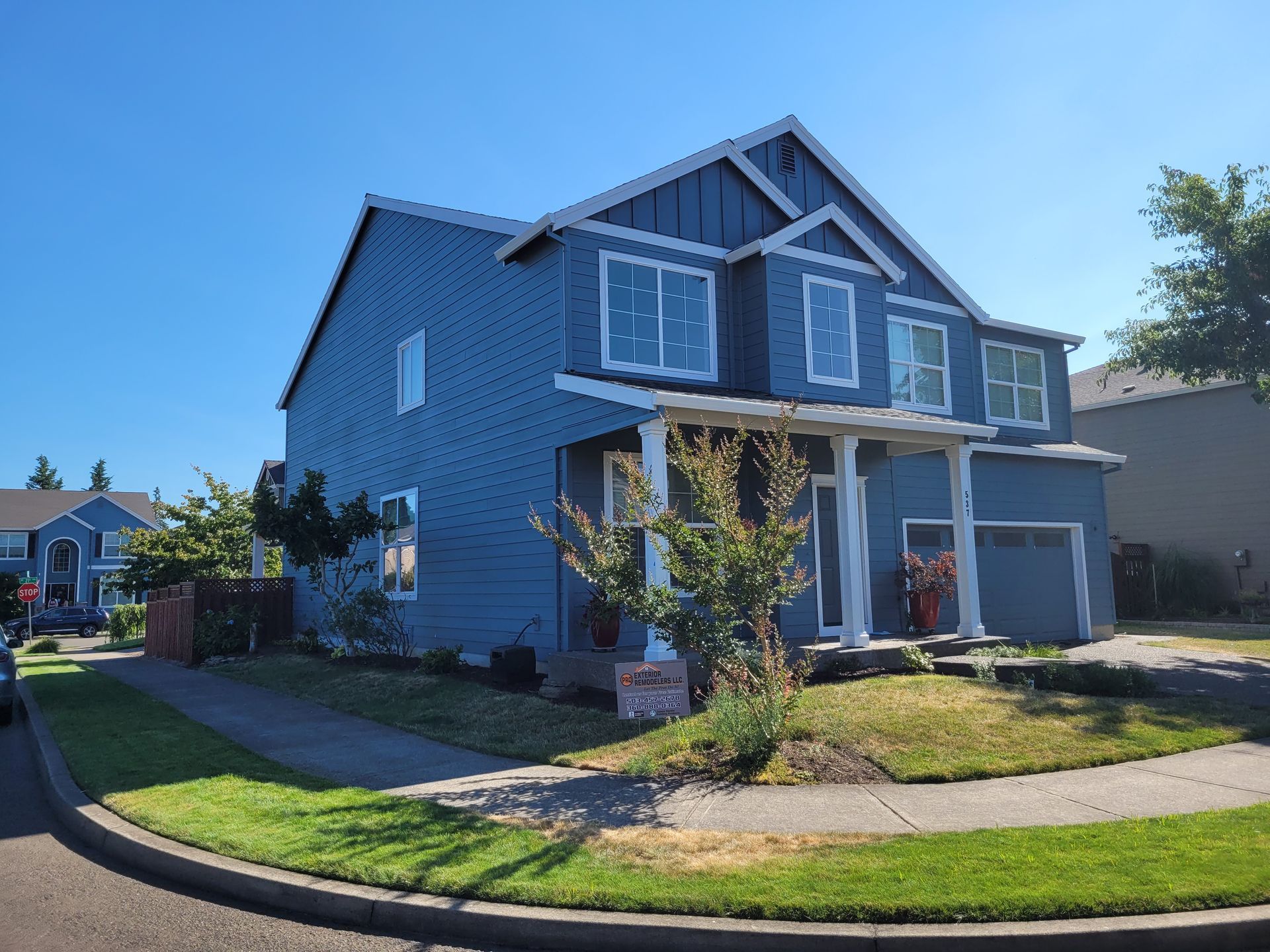A large blue house with a lot of windows is sitting on top of a lush green lawn.