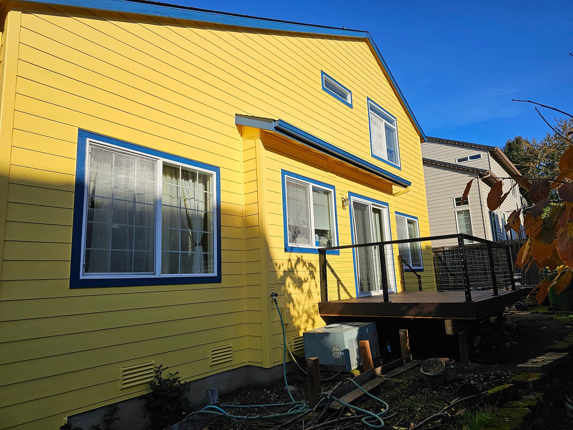 A yellow house with blue trim and a deck
