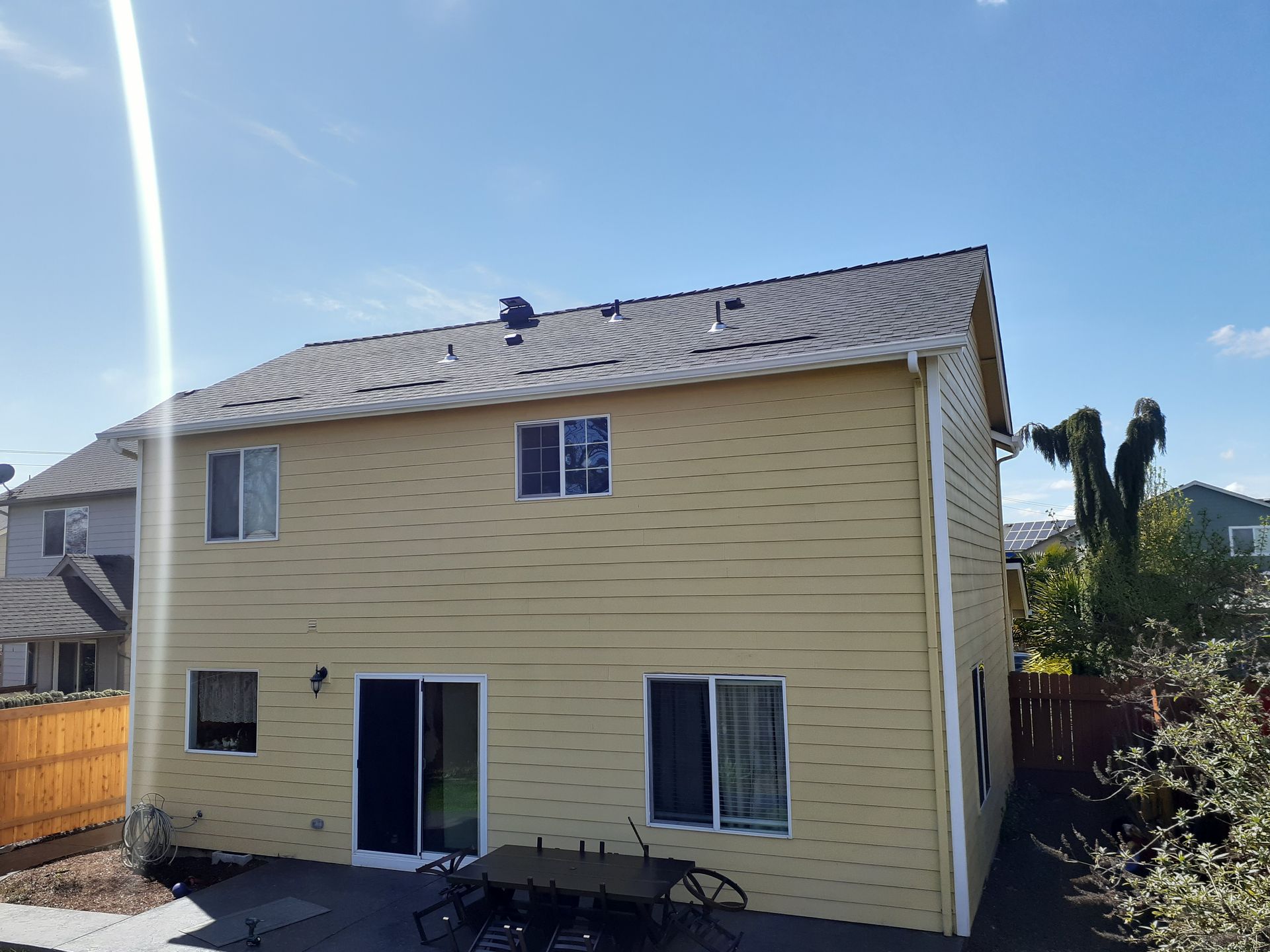 The back of a house with a patio and a table and chairs on it.
