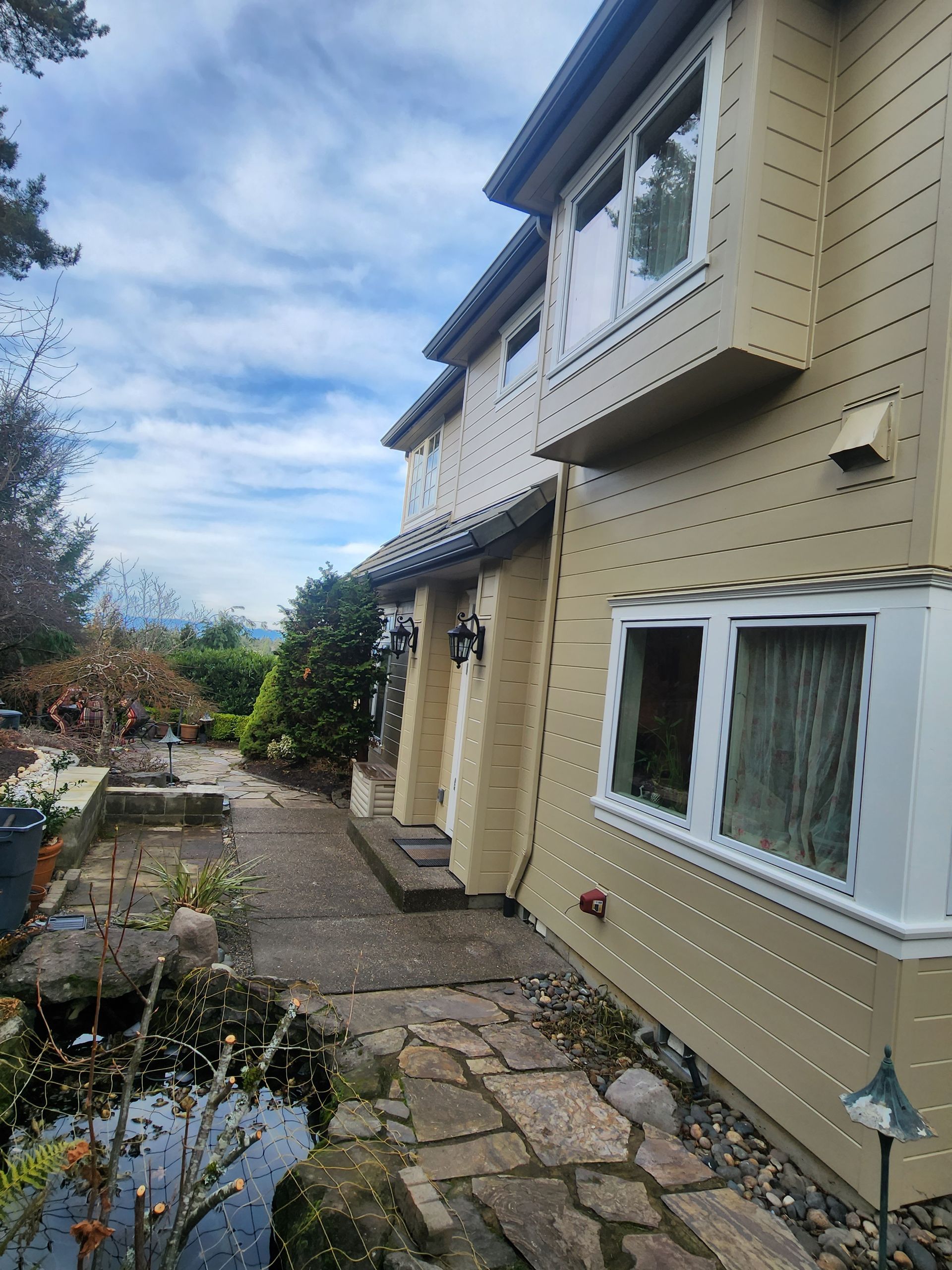 A large house with a patio and a pond in front of it.