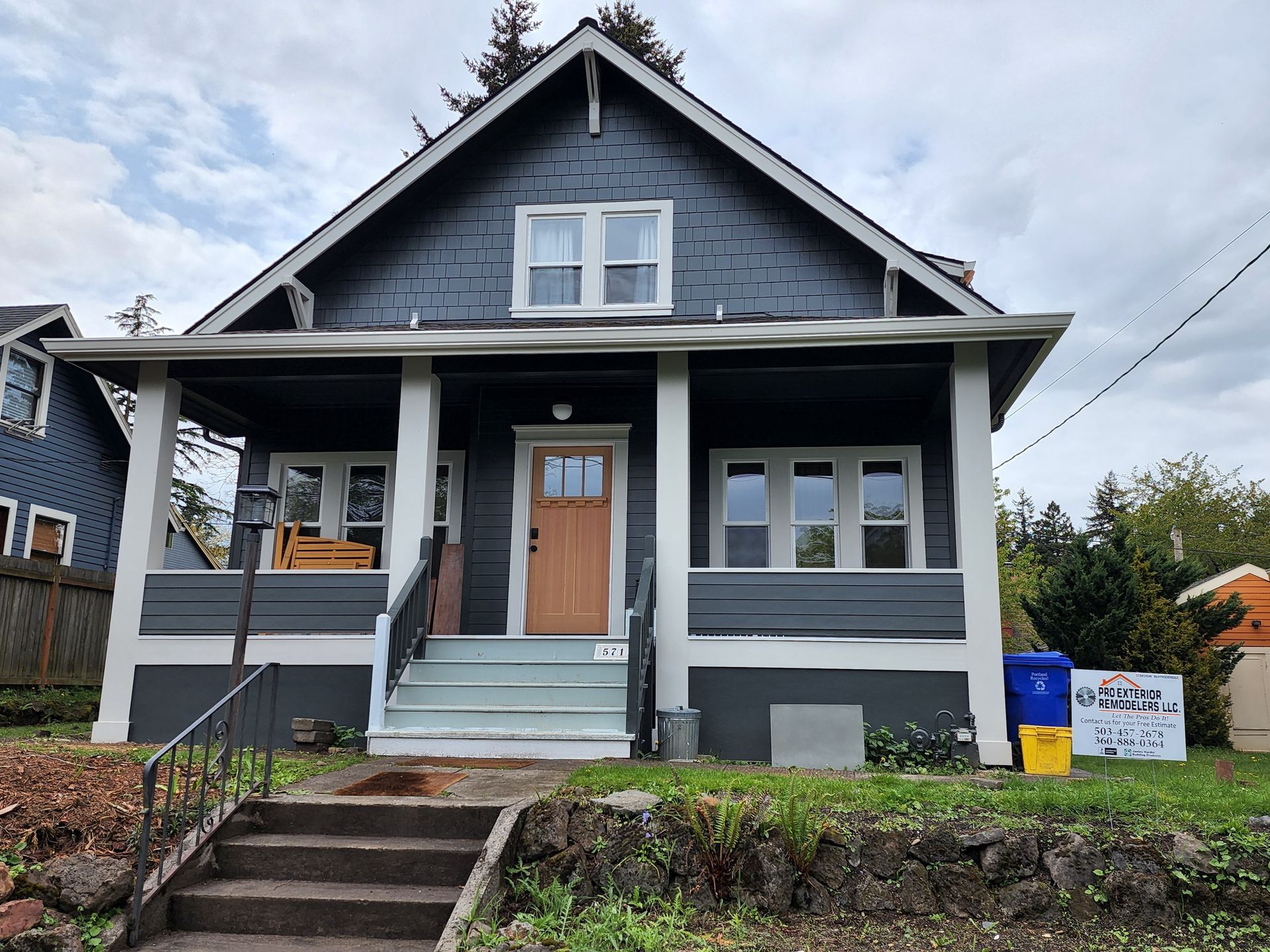 A gray house with a porch and stairs in front of it.
