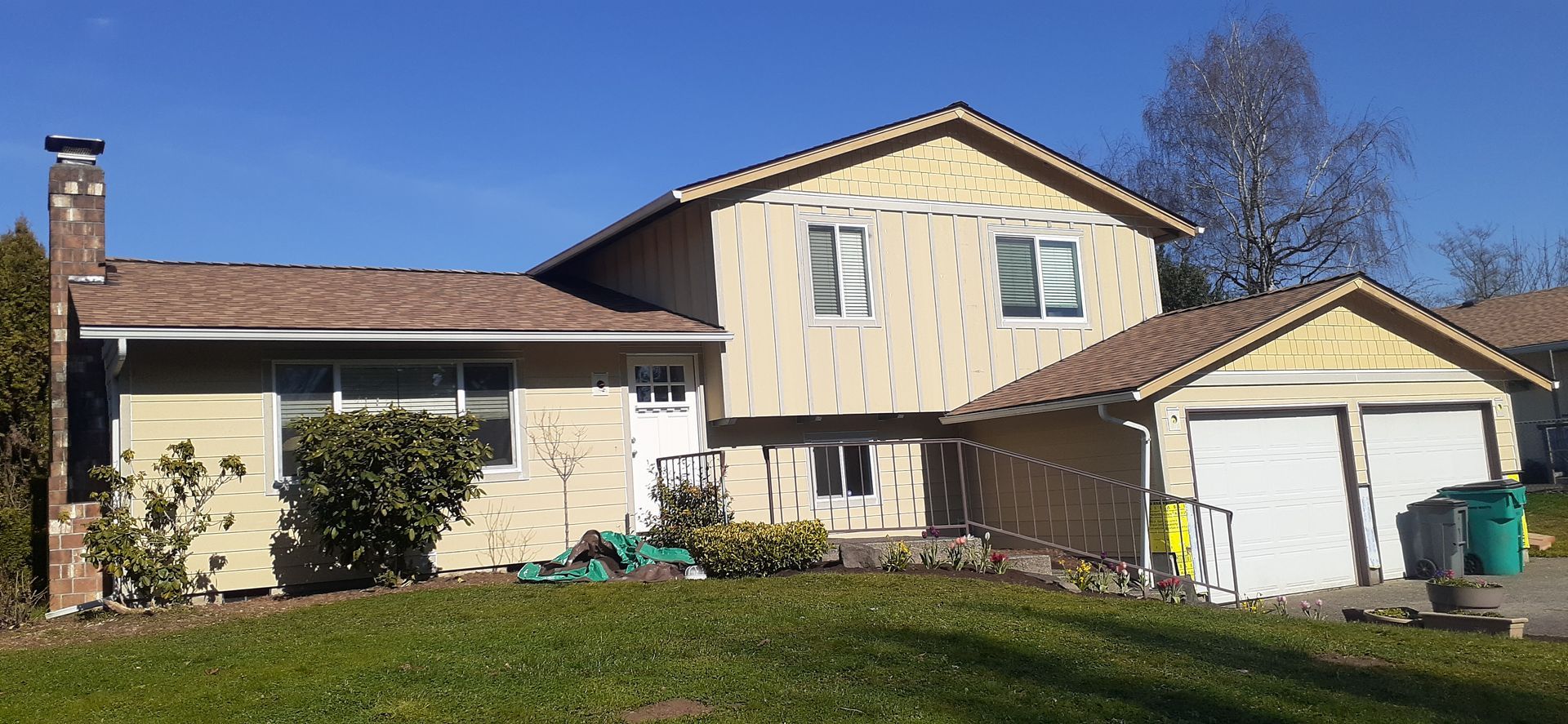 A large house with a garage and a chimney is sitting on top of a lush green lawn.