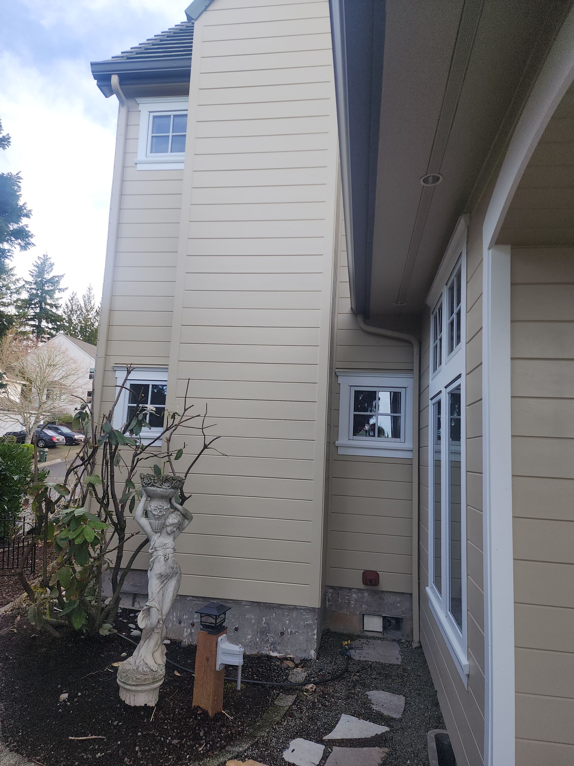 The side of a house with a statue in front of it.