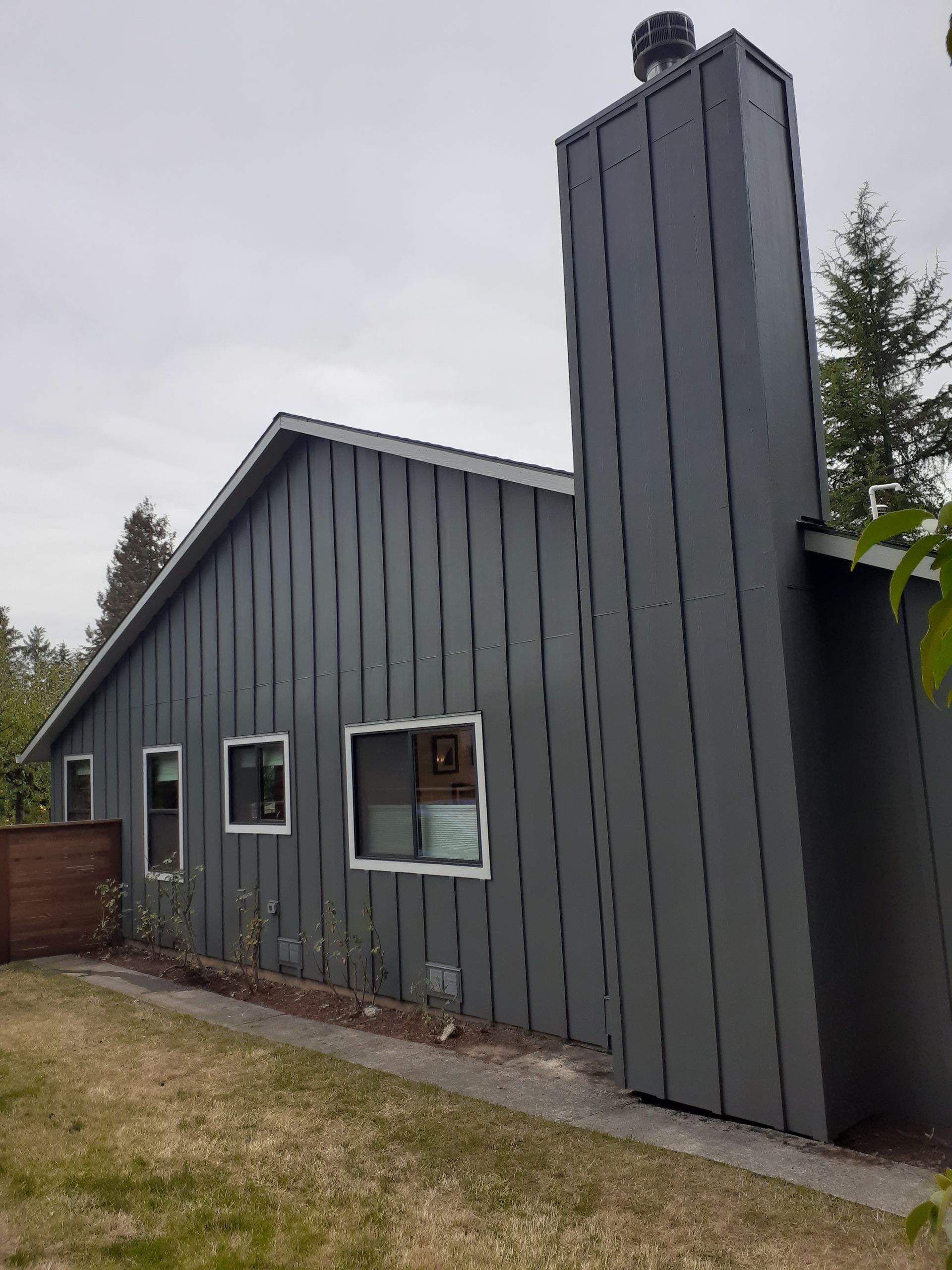 A gray house with a chimney on the side of it.