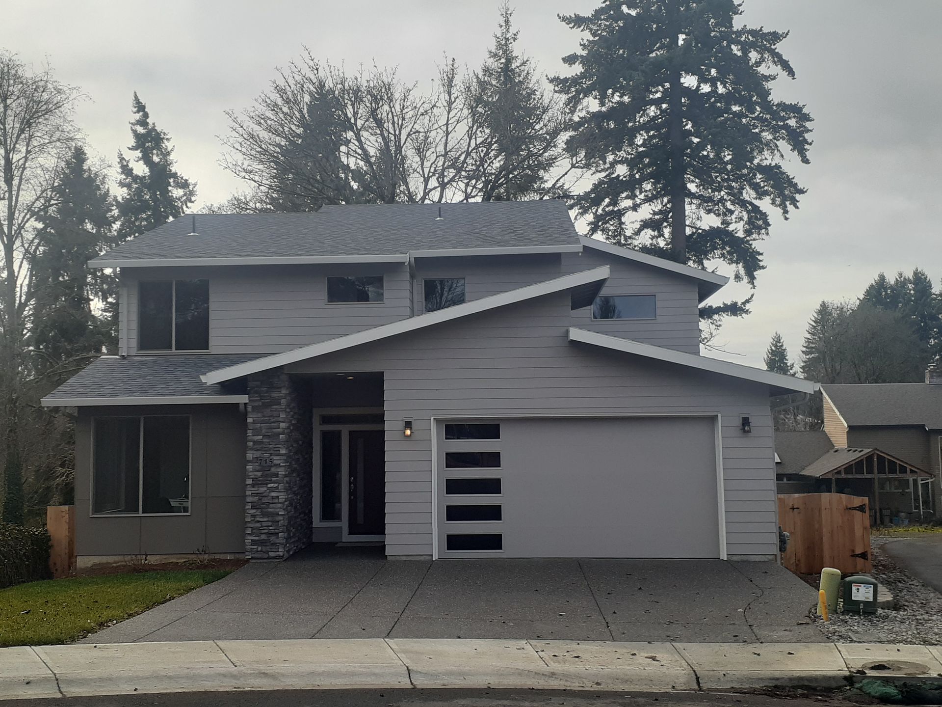 A house with a gray roof and a black garage door