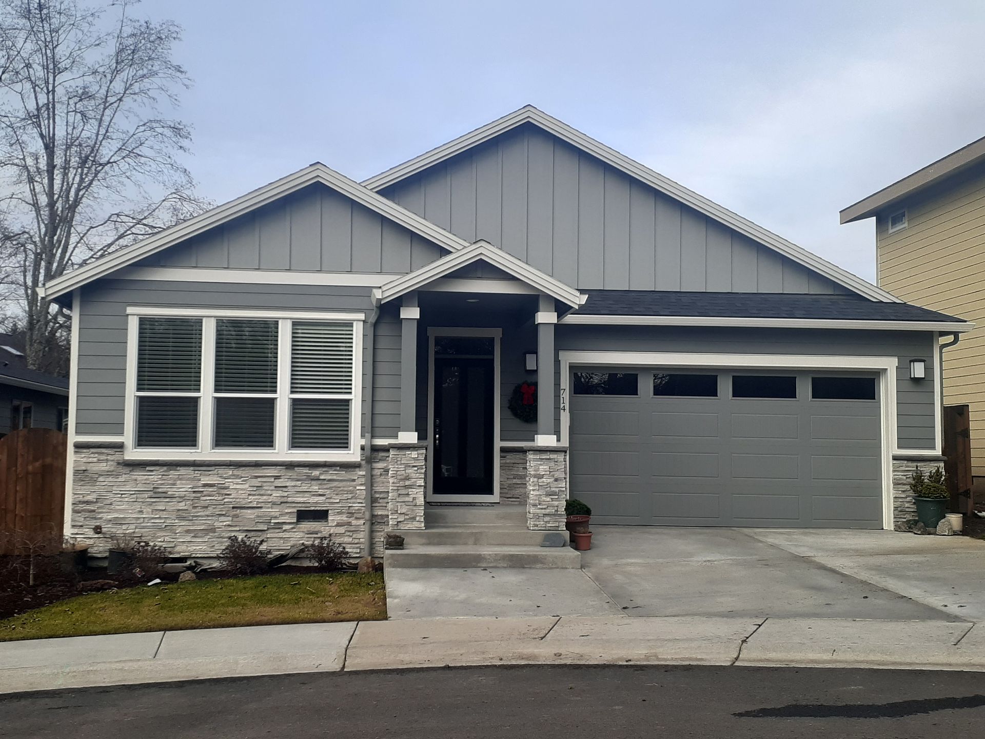 A gray house with a garage and a stone facade