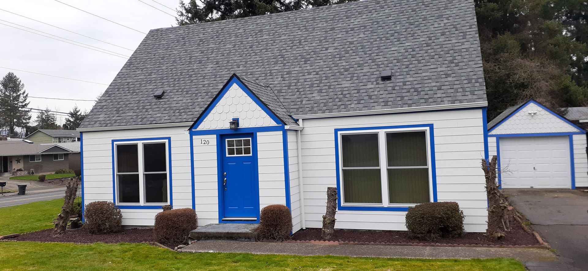 A white house with blue trim and a gray roof.
