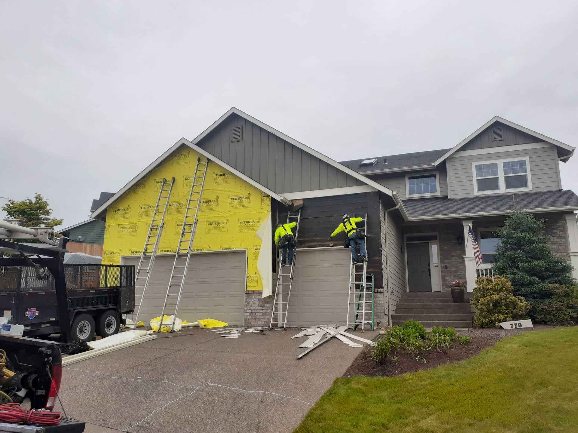 A house is being remodeled with yellow siding and a forklift is parked in front of it.