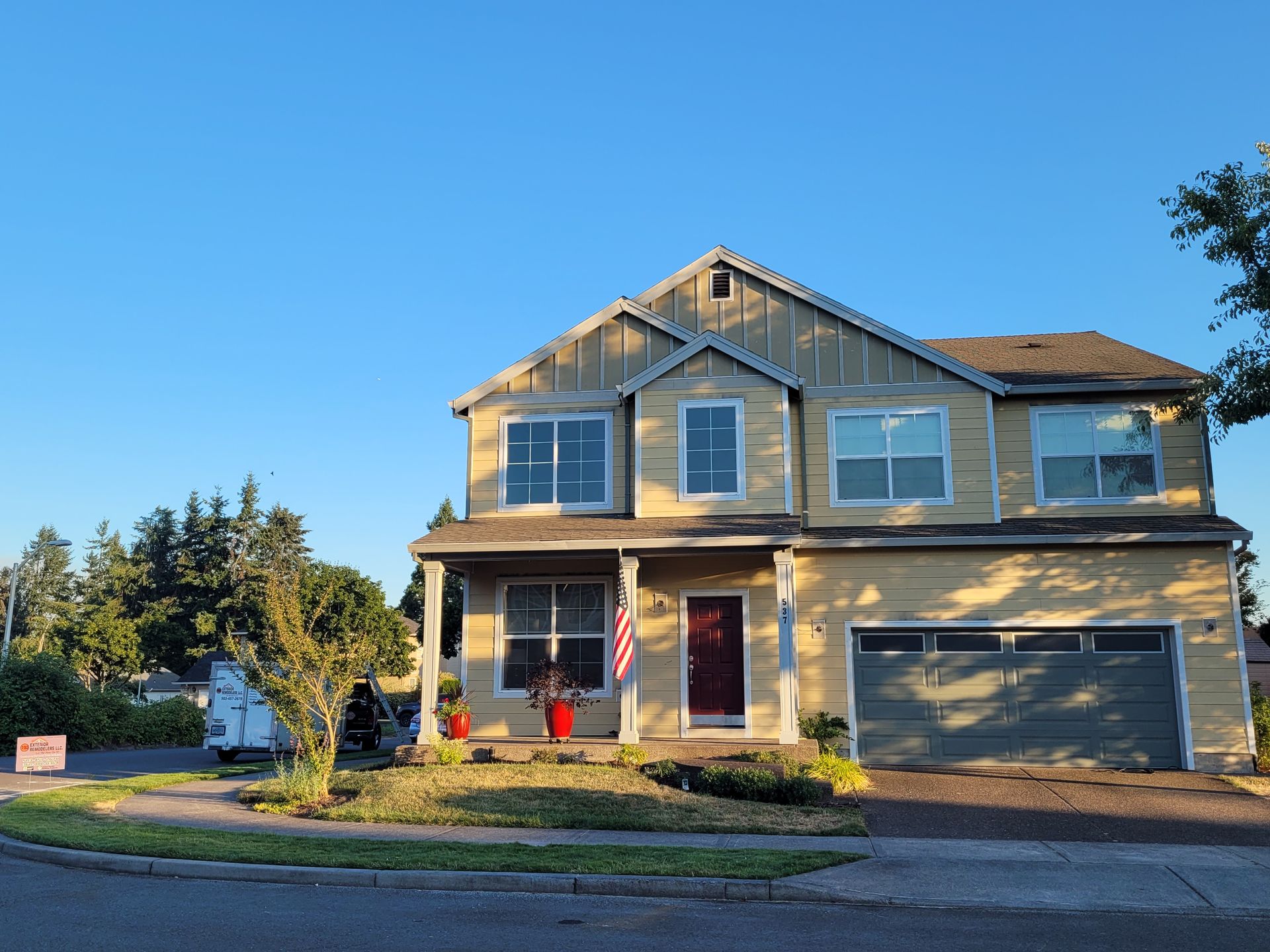 A large yellow house with a red door and a blue sky in the background.