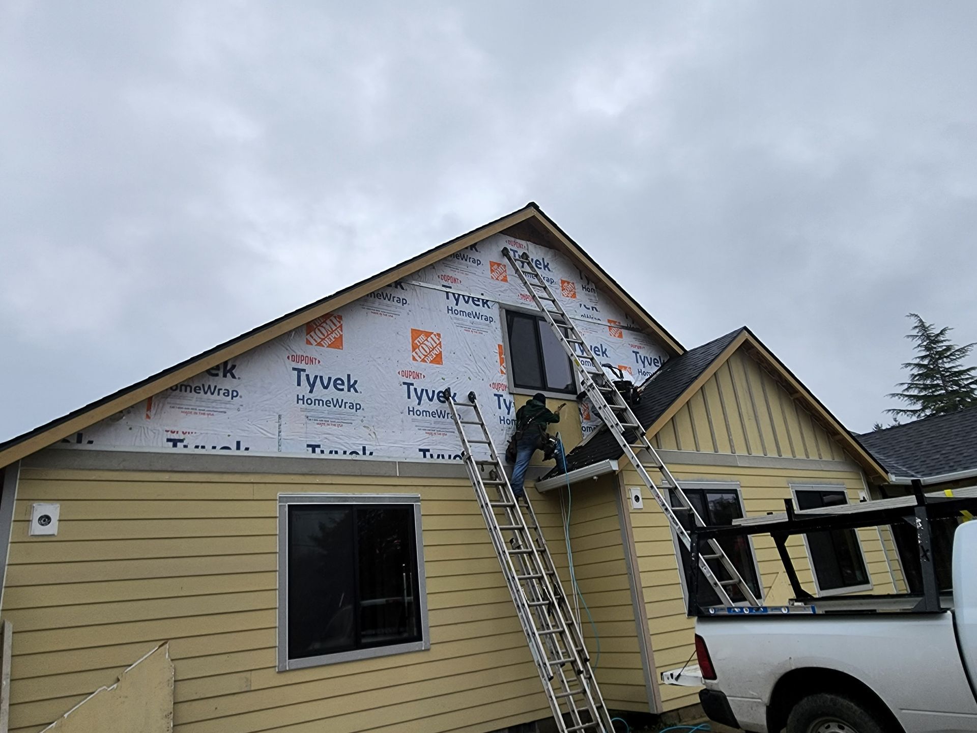 A white truck is parked in front of a house that is being remodeled