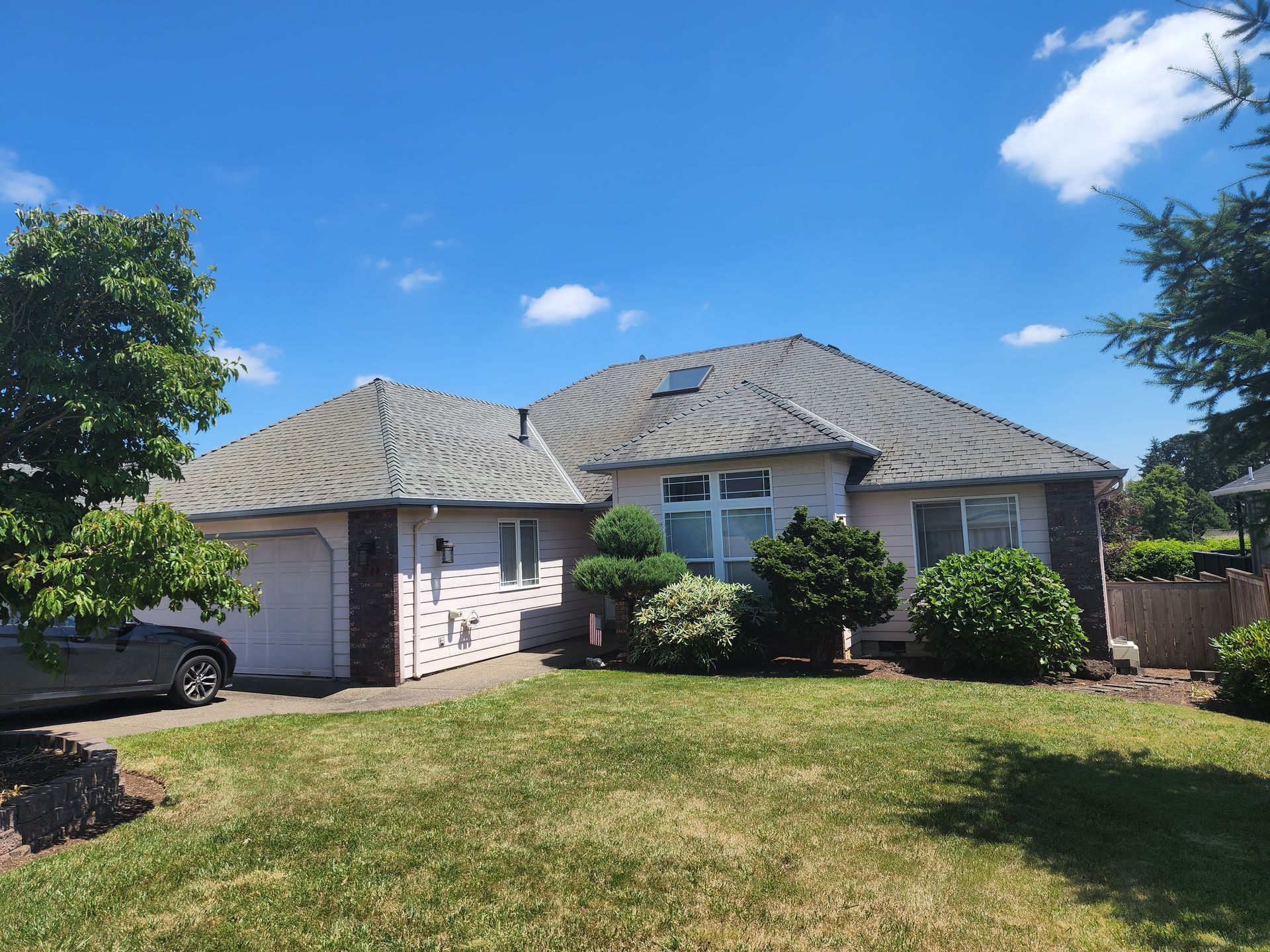 A white house with a gray roof and a car parked in front of it.